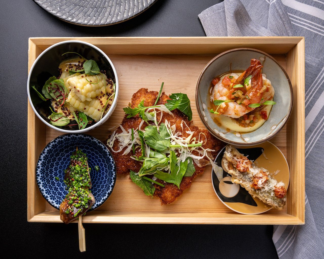 A bento boz with four small dishes and a crispy chicken cutlet at the center