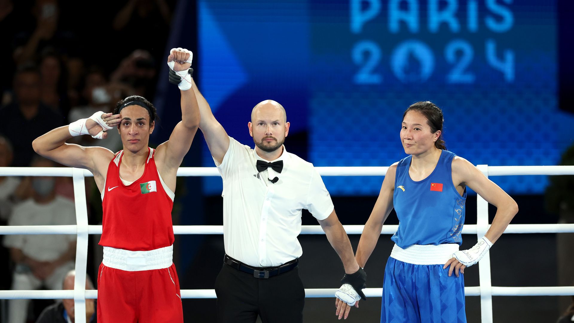 Liu Yang of Team China looks on as Match Referee Jakov Peterson raises the hand of Imane Khelif of Team Algeria to announce the winner of the Boxing Women's 66kg Final match at the Paris Olympics