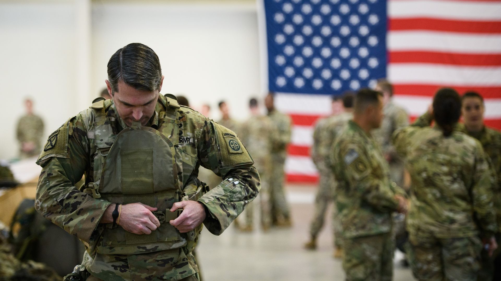 In this image, an army member puts on a vest