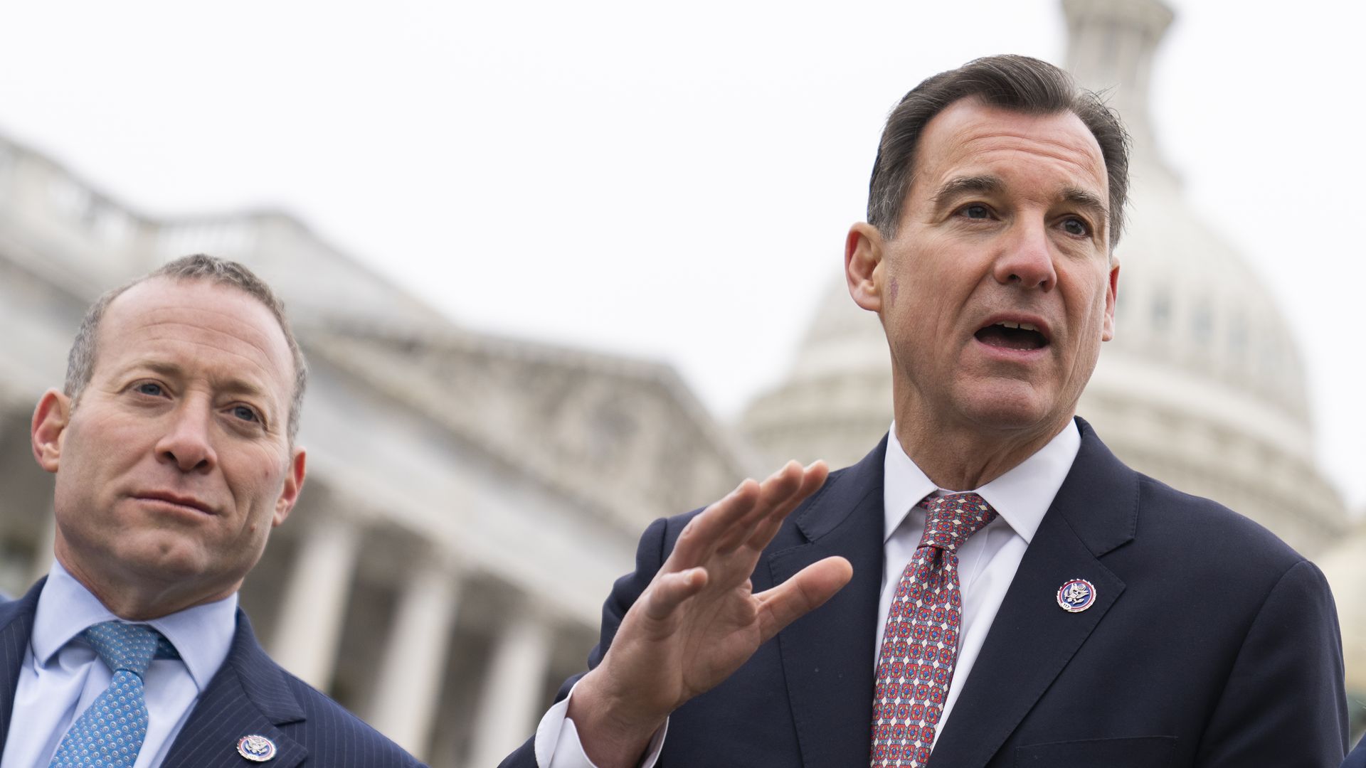Reps. Josh Gottheimer, wearing a blue suit, light blue shirt and teal tie, and Tom Suozzi, wearing a dark blue suit, white shirt and red tie.