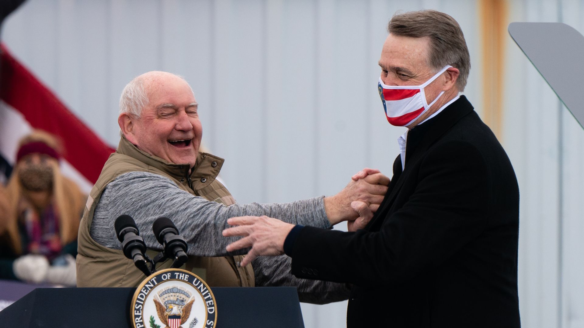 Sonny and David Perdue laughing and shaking hands