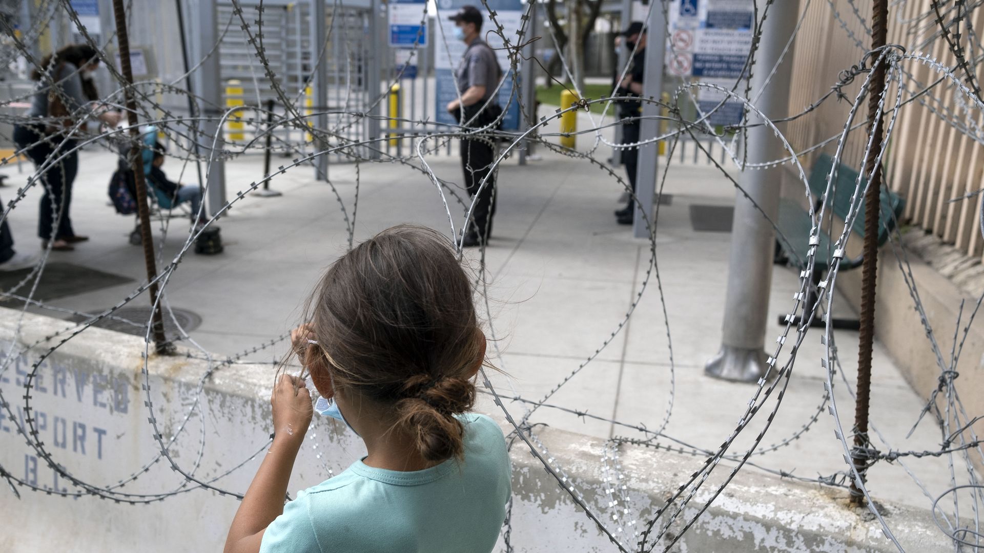 A migrant girl looks at asylum seekers entering the United States at the San Ysidro crossing port in Tijuana, Baja California State, Mexico, on May 10