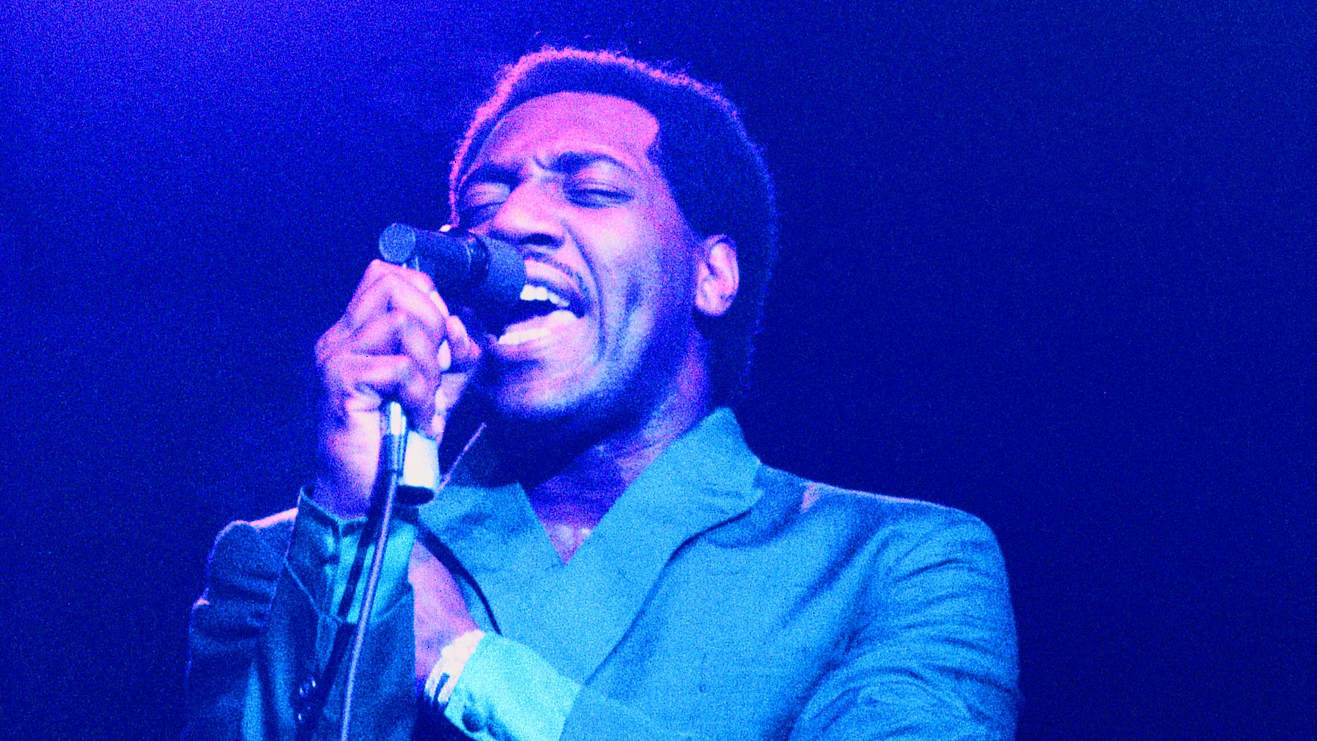 Otis Redding sings into a microphone.