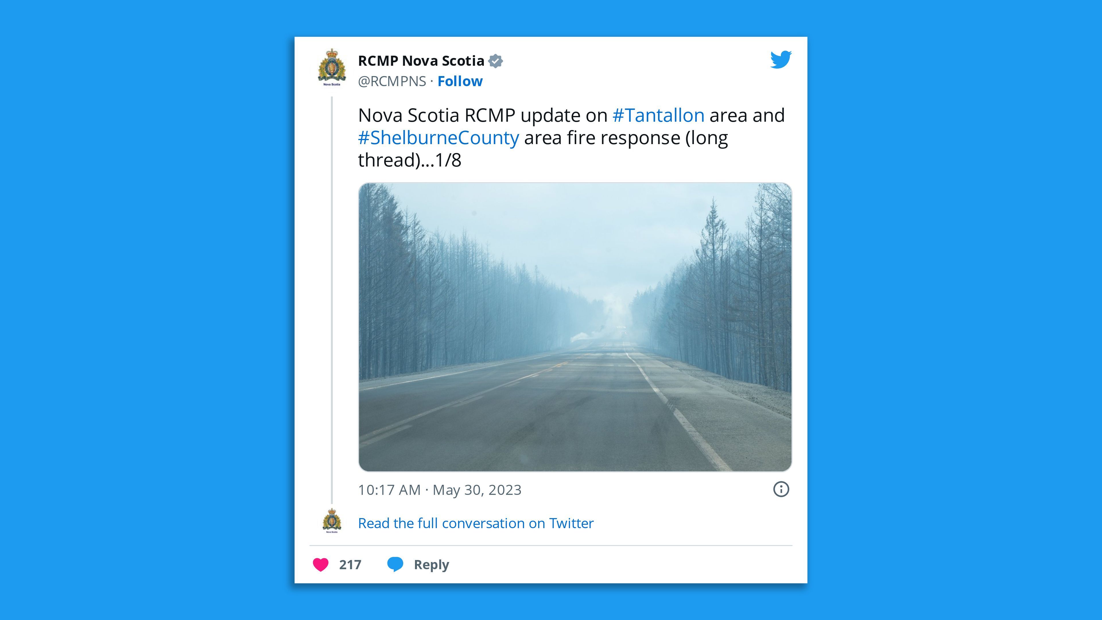 A screenshot of a Royal Canadian Mounted Police Nova Scotia photo tweet showing a smoke-filled road lined by forest trees.