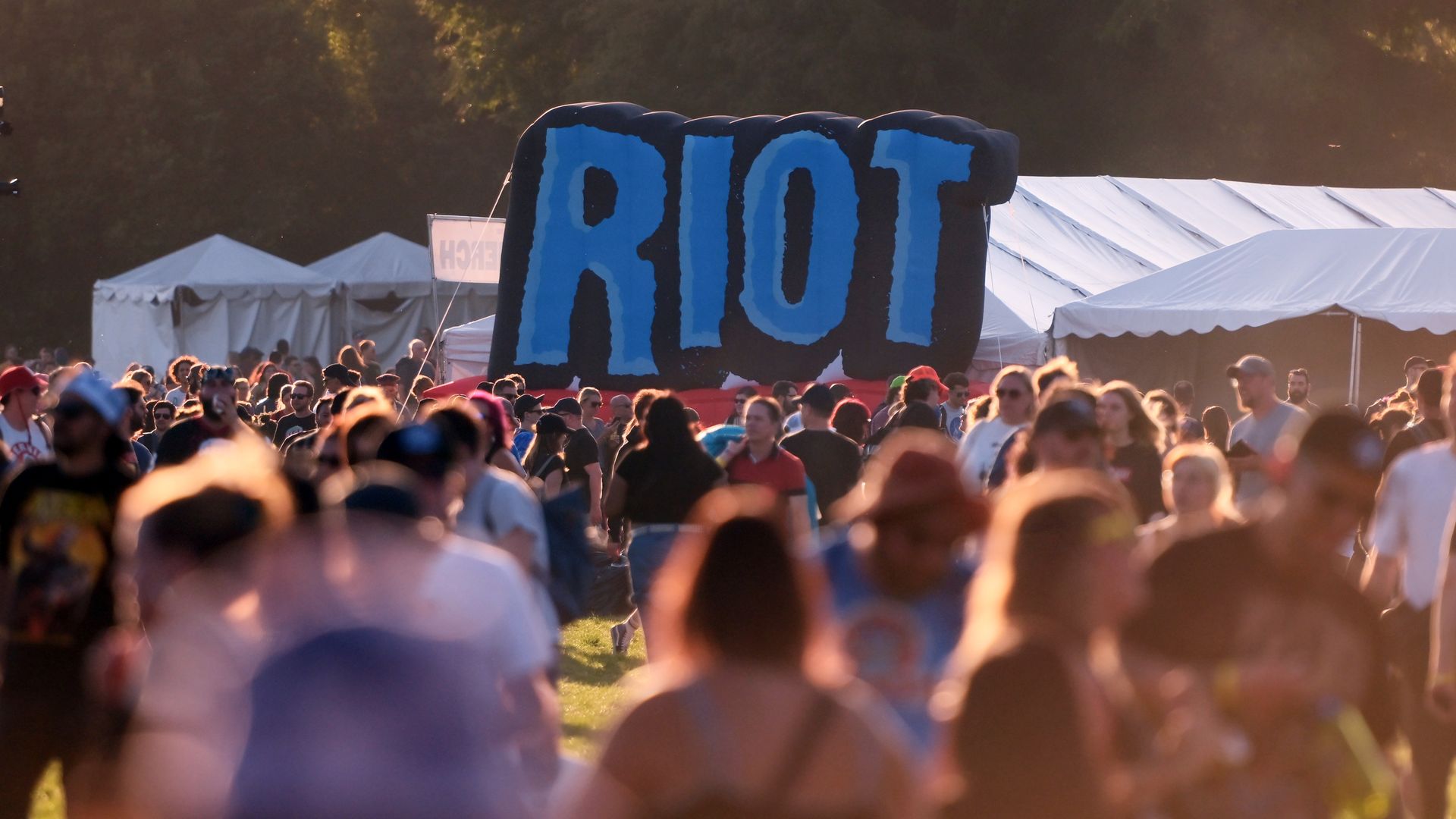 Photo of a crowd at a music festival with a sign that says "riot" 