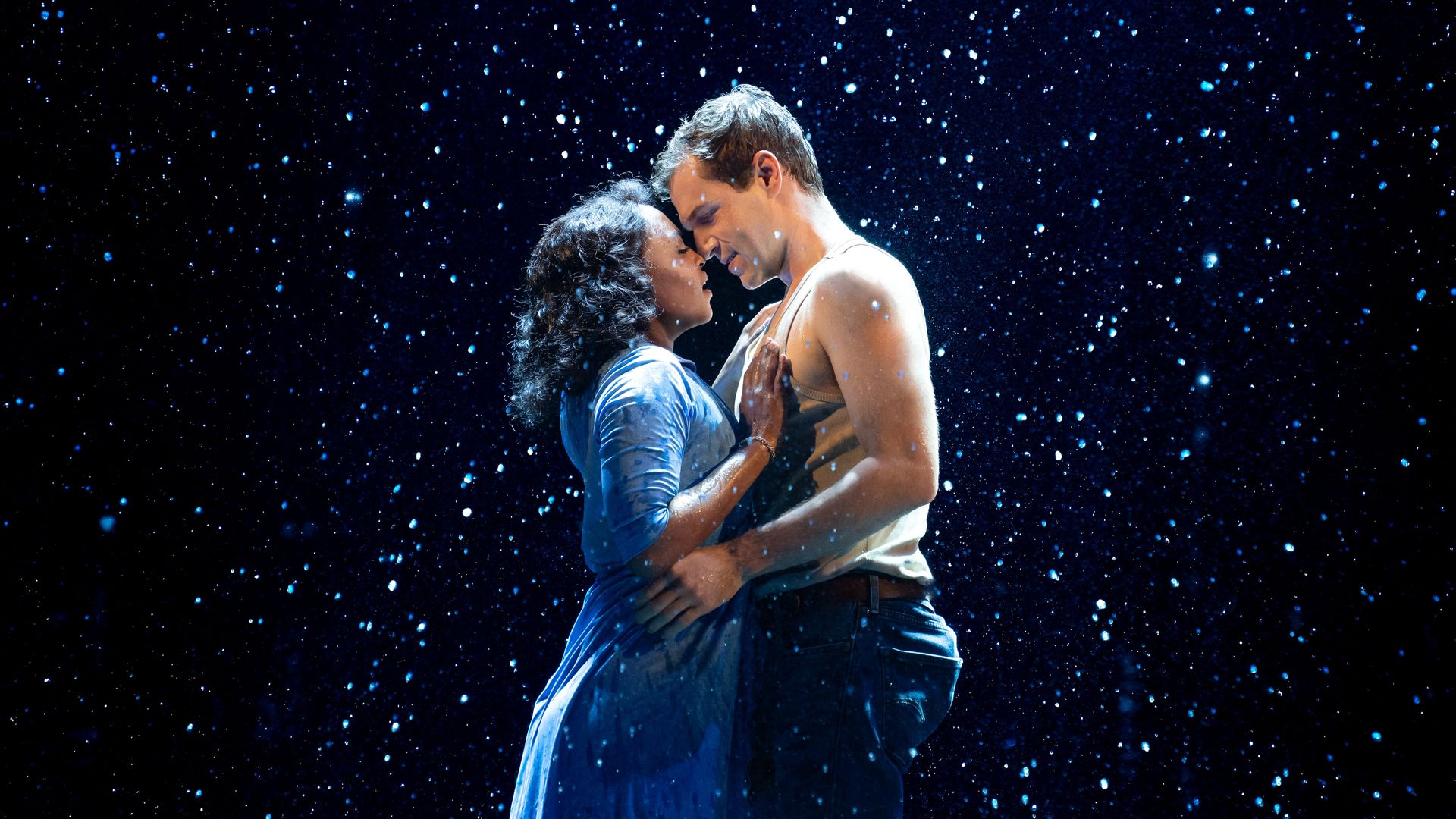 Two performers from the musical "The Notebook" on stage during the iconic rain scene. 