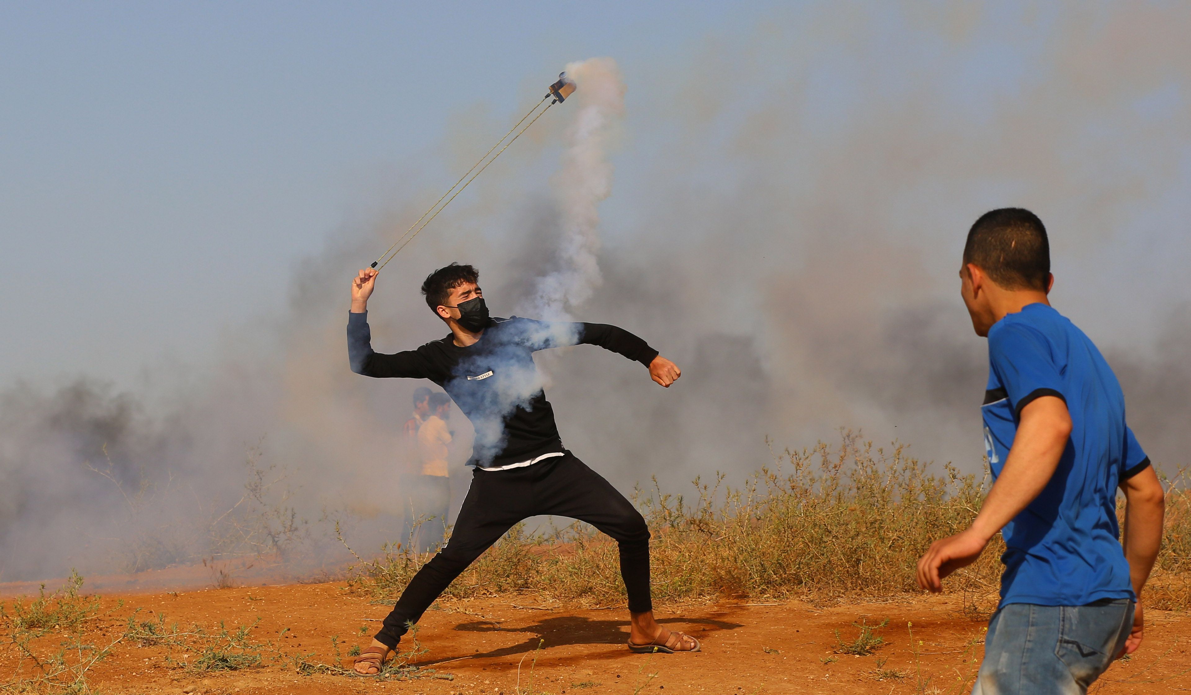 Palestinian protesters throw back a tear gas canister to Israeli forces during a protest against Israeli attacks against Palestinian worshippers at Al-Aqsa Mosque 