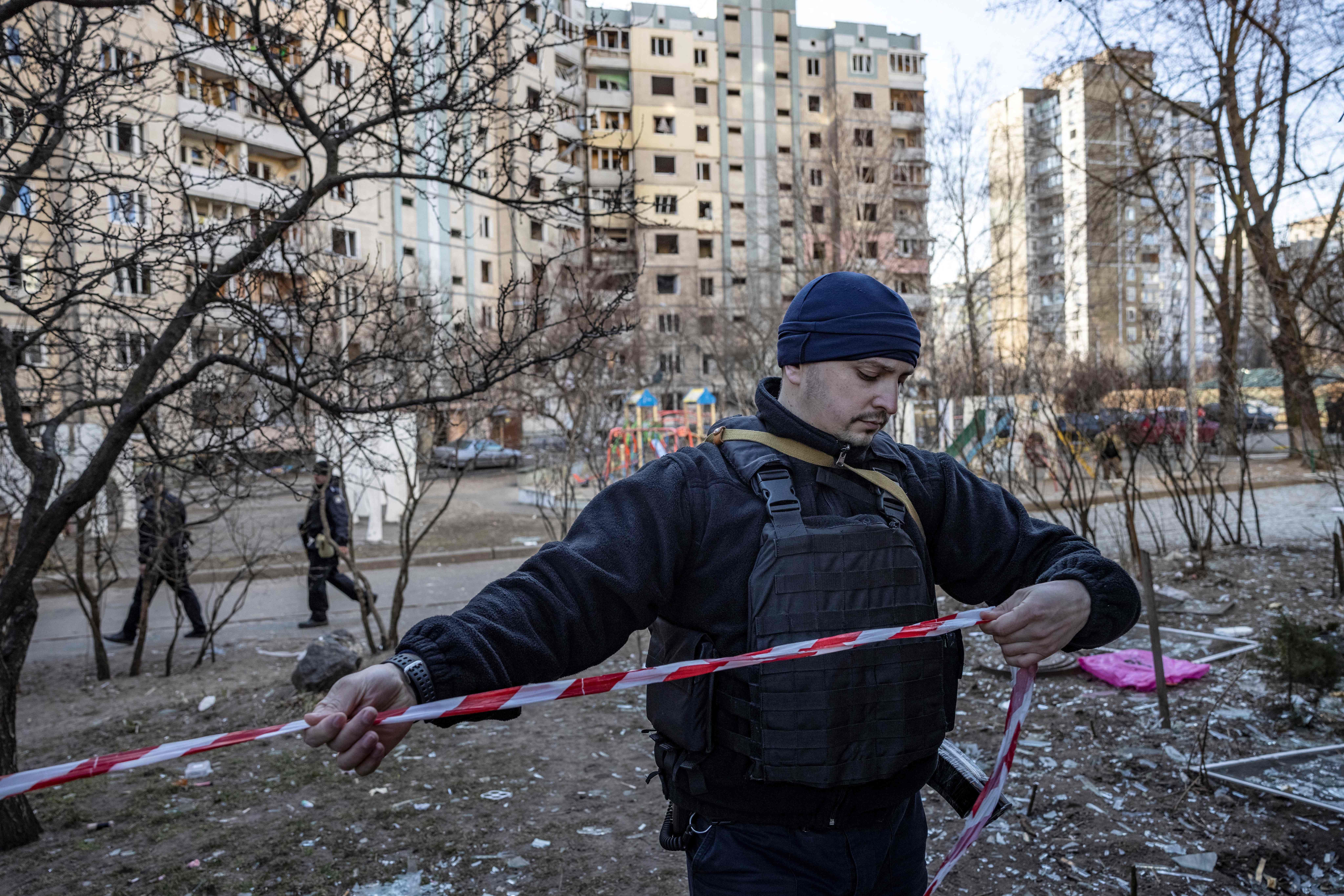 A Ukrainian police officer cordons off an area near a residential building which was hit by the debris from a downed rocket, in Kyiv, on March 20.
