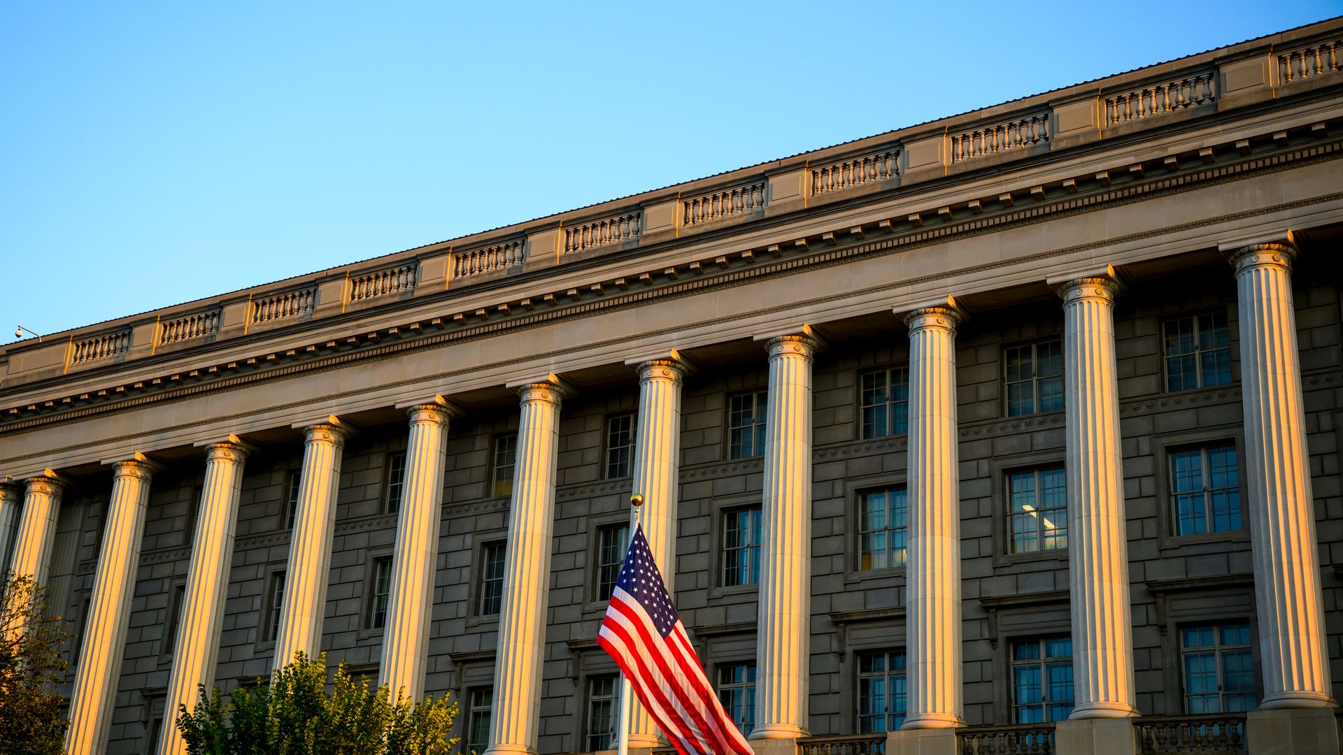 An American flag flies outside the IRS building, which has large, round columns.