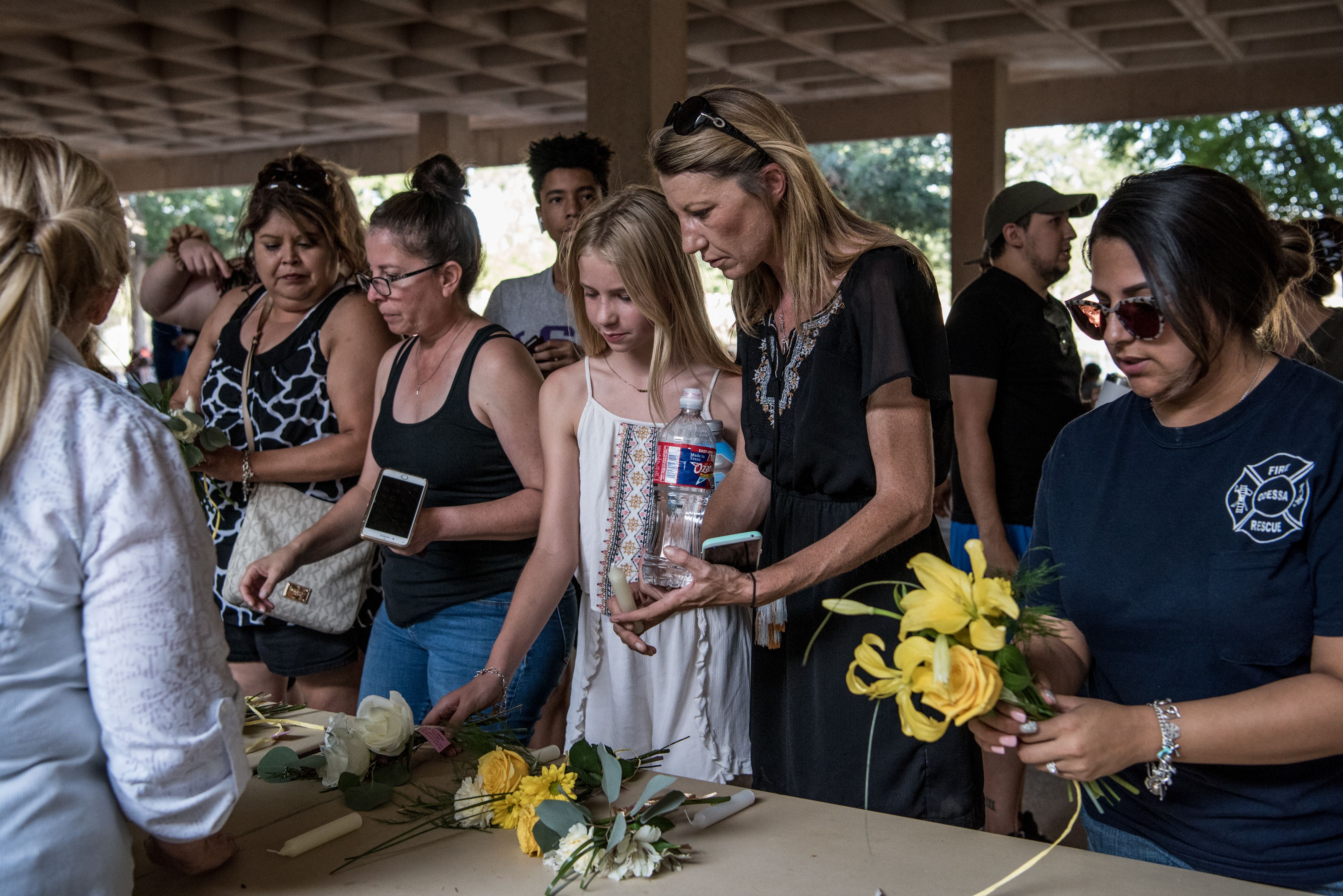 Lindsey Clark and her daughter Caitlin Clark take small flower bouquets provided by local Odessa residents before a prayer vigil at the University of Texas of the Permian Basin