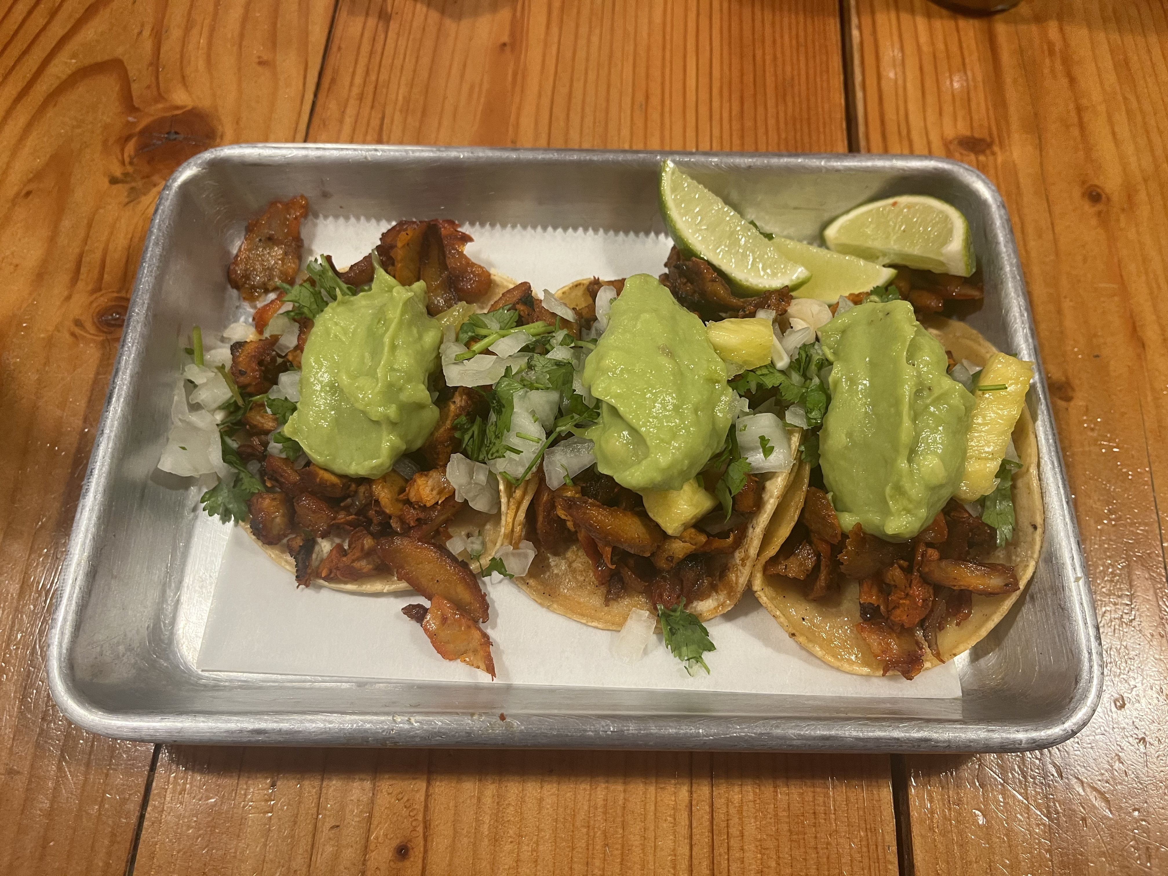 Al pastor tacos on a metal tray.