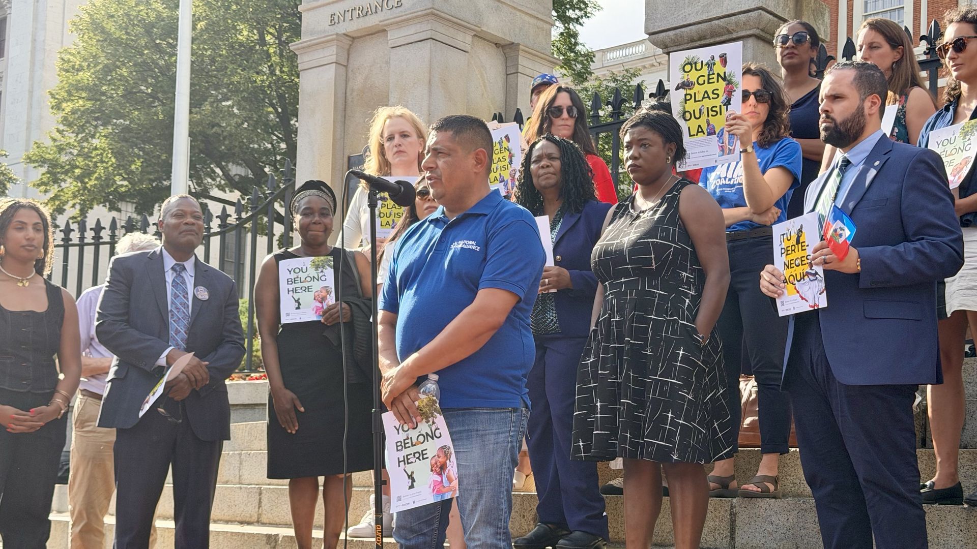 Jose Palma, a Massachusetts TPS holder from El Salvador, stands at a mic surrounded by a crowd of TPS recipients, advocates and elected officials in front of the State House on June 25, 2026, after the Supreme Court ruling on TPS for Haiti.