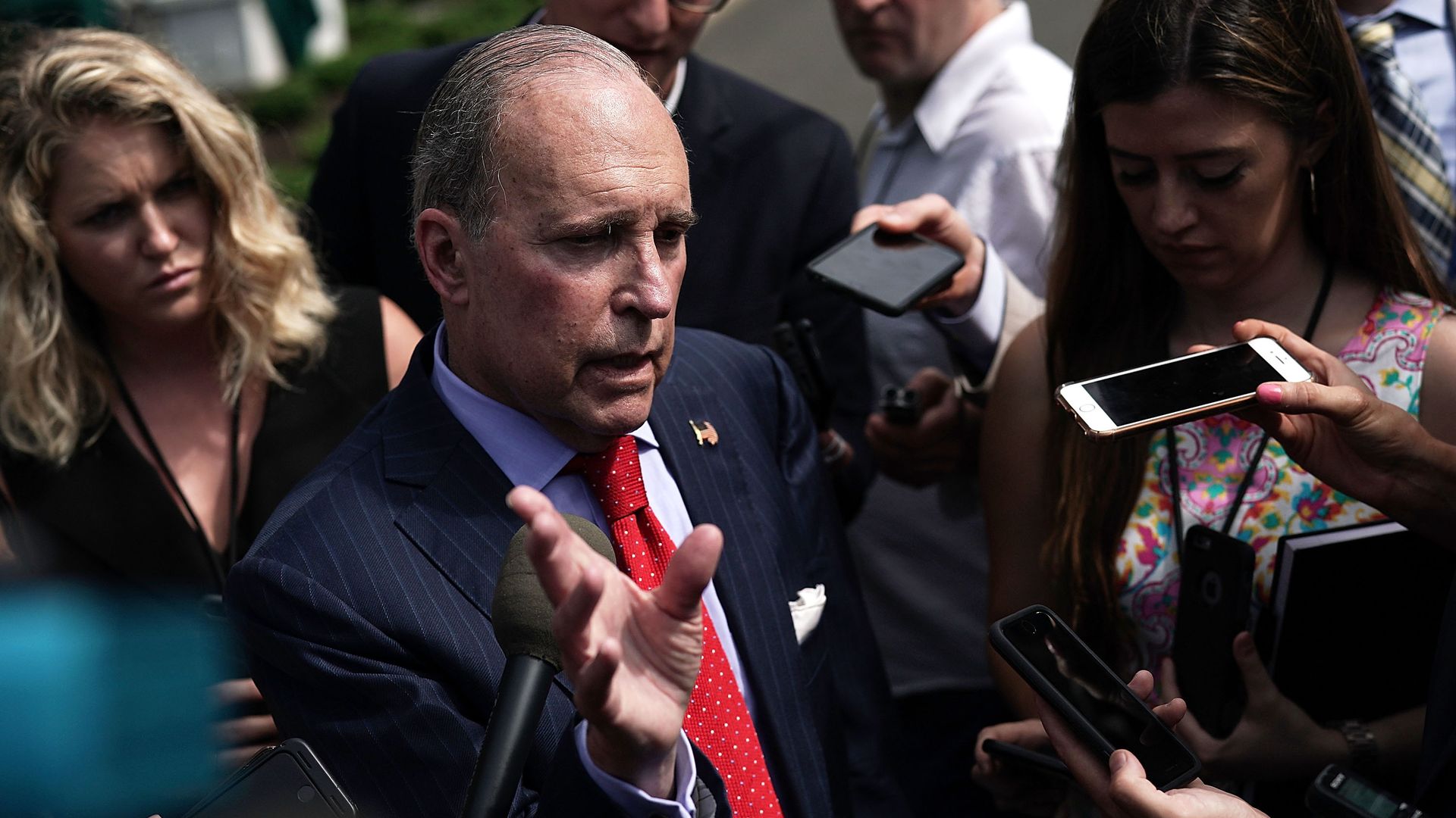 Larry Kudlow in the middle of a crowd of reporters 