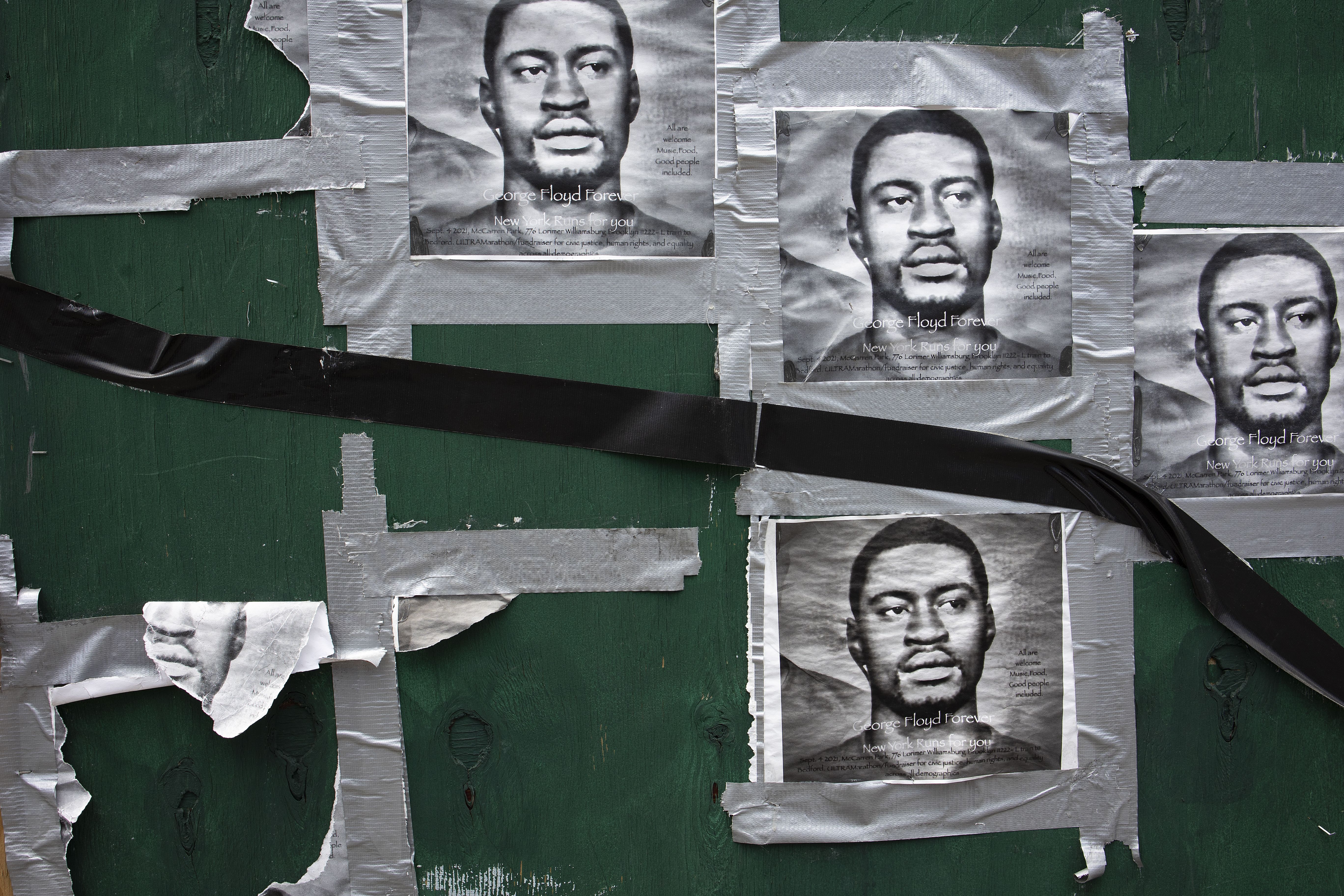 Photo of posters that depict George Floyd taped on a green wall