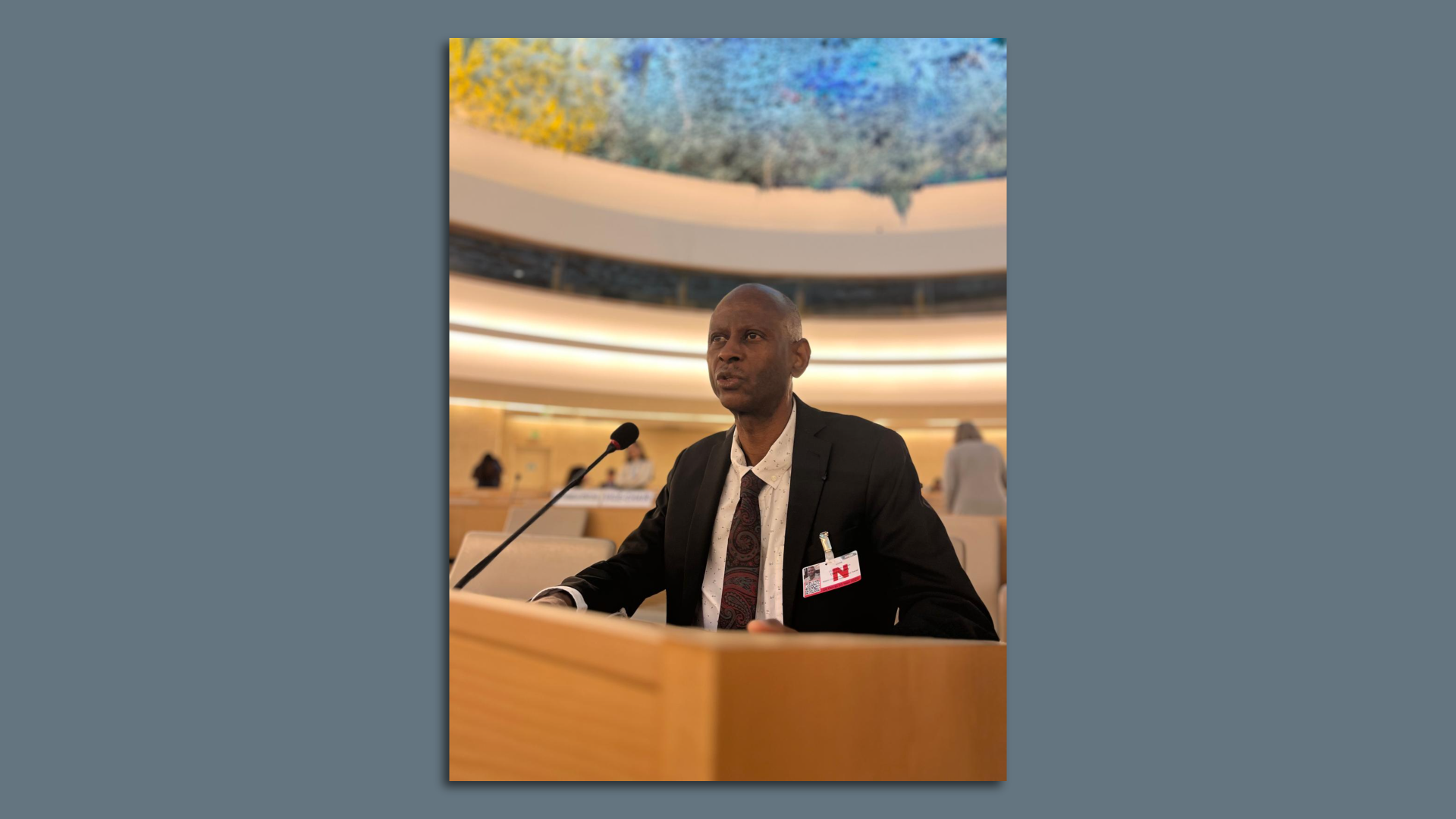A man in a suit speaks at a podium 