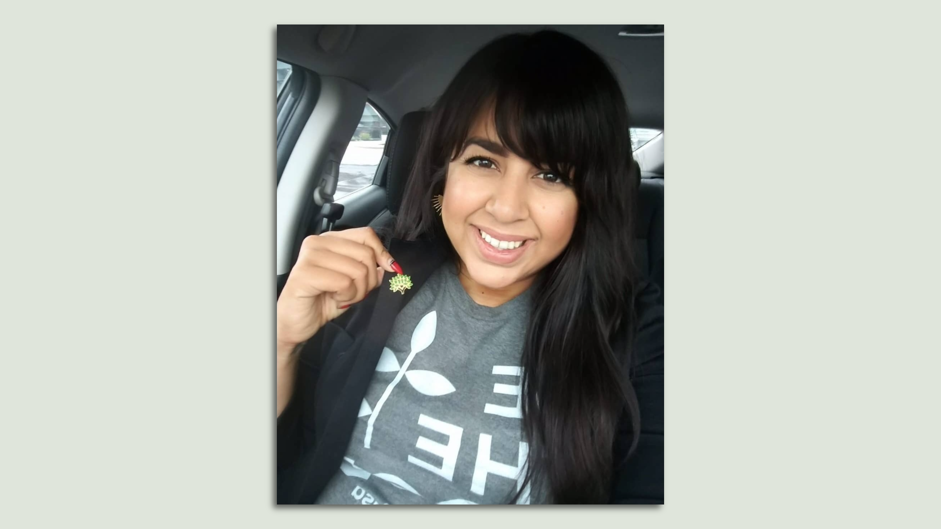 A selfie of Stephanie Cedeño holding her coat to show a pin of the Besa logo