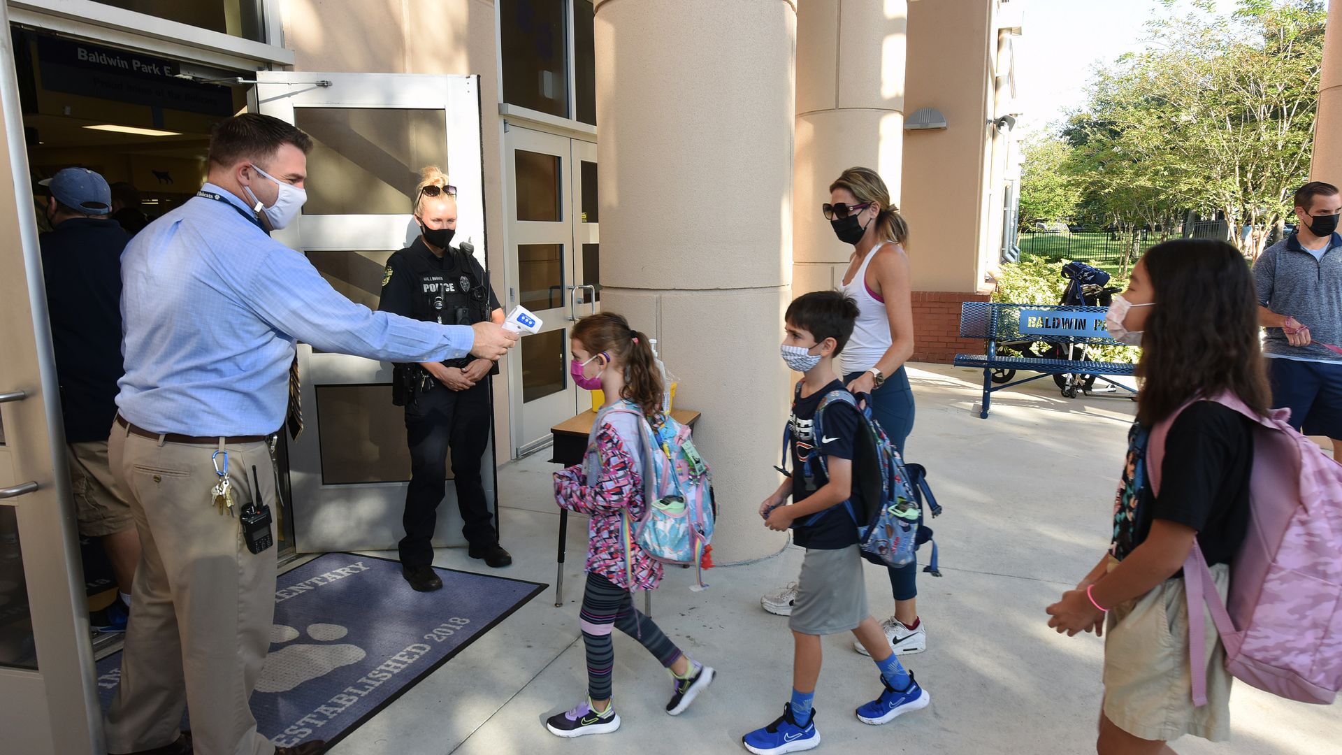 Principal Nathan Hay performs temperature checks on students as they arrive on the first day of classes for the 2021-22 school year at Baldwin Park Elementary School.
