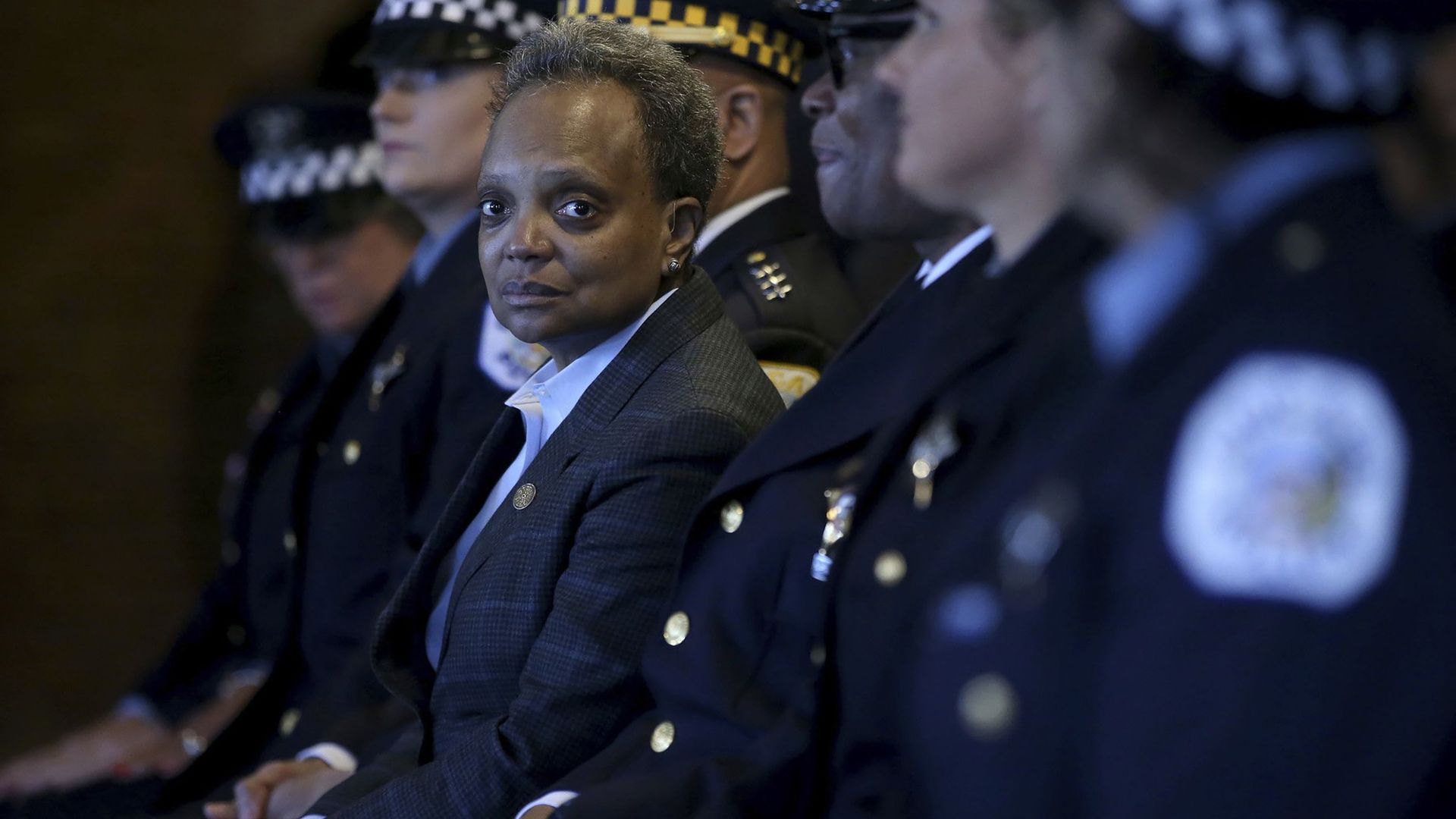 Photo of a woman sitting next to uniformed police officers. 