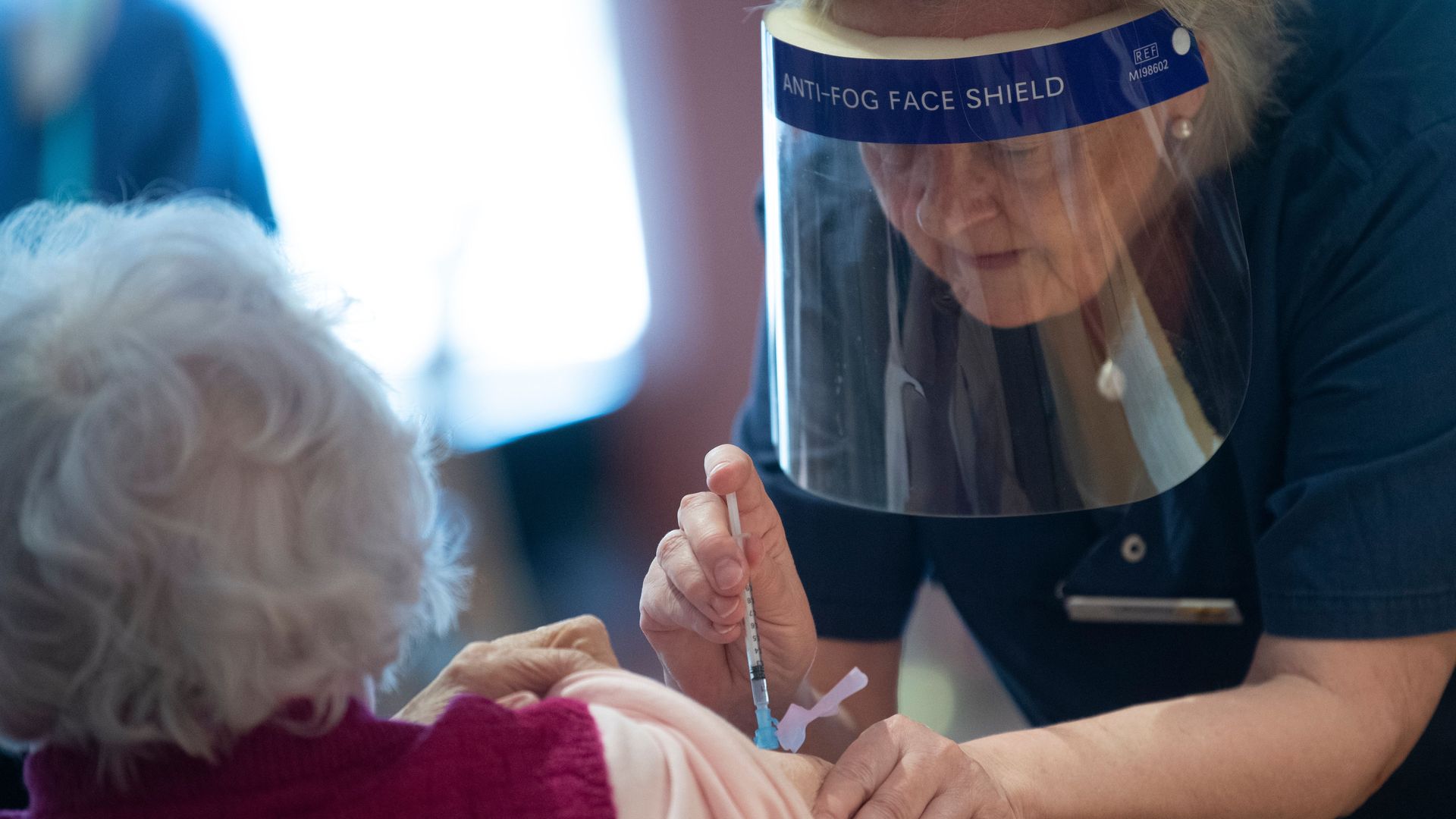 Picture of a health care worker in Sweden vaccinating an elderly woman