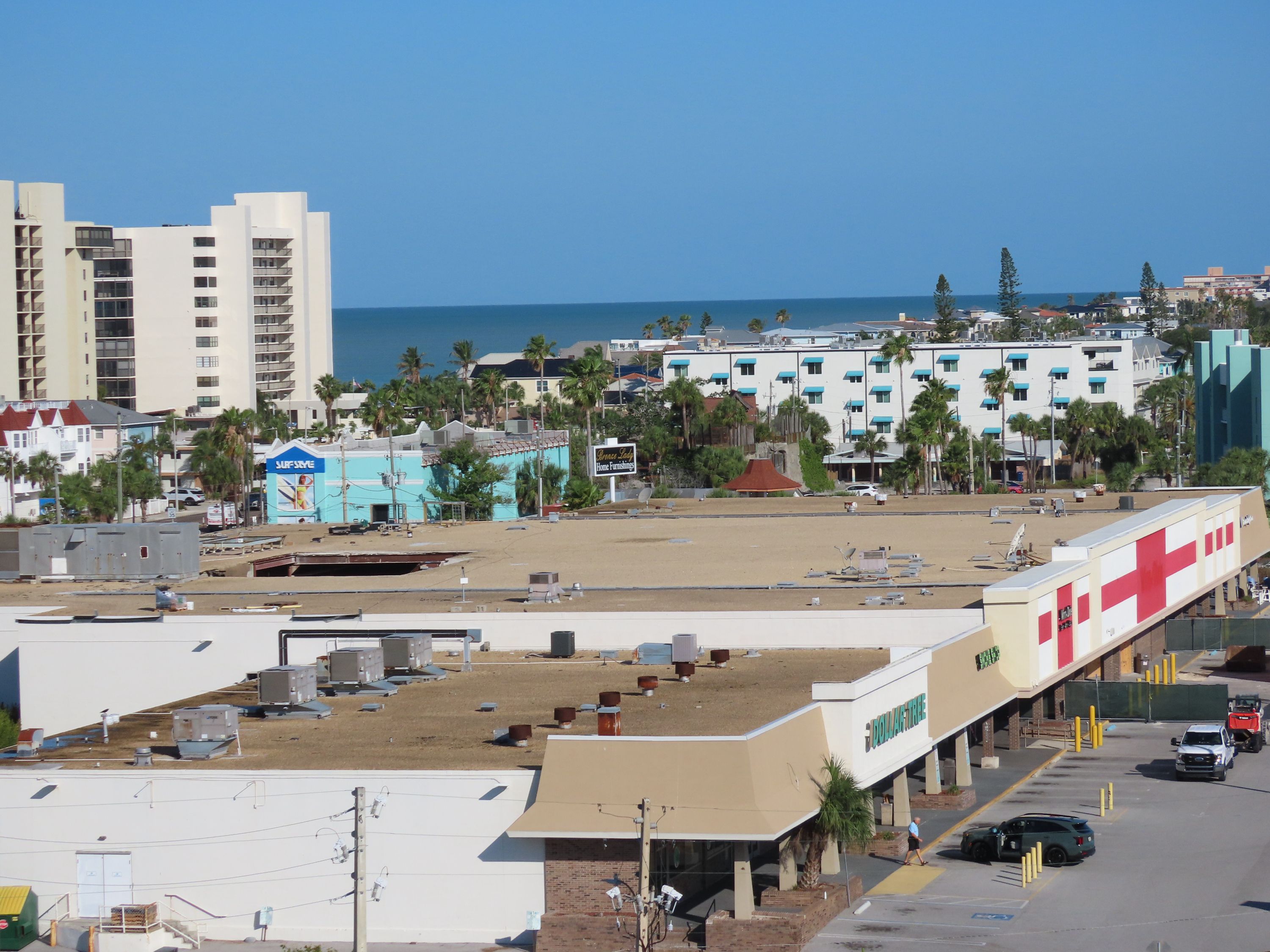 Coastal cityscape featuring a gravel roof with a gaping hole on the left side. 