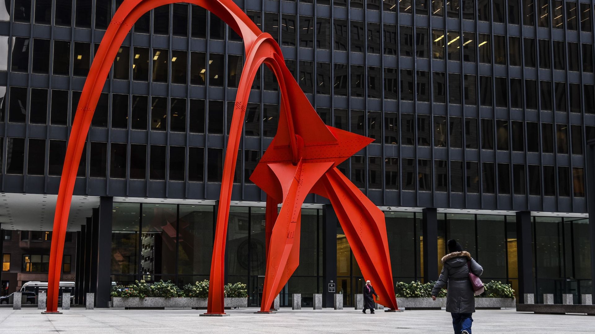 Alexander Calder's bright orange "Flamingo" sculpture in front of a black modern building.