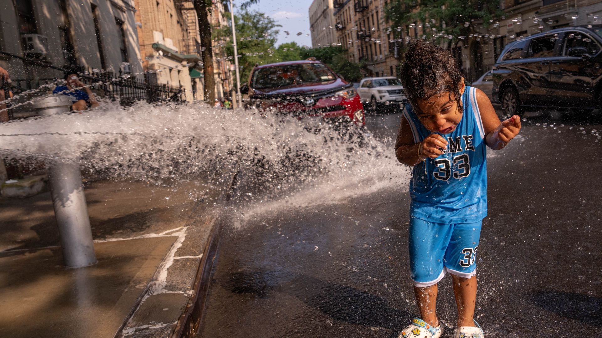 "A 3-year-old cools off beside a fire hydrant on Tuesday during hot weather in the Washington Heights neighborhood of New York City on Tuesday during the third heat wave of the season. 