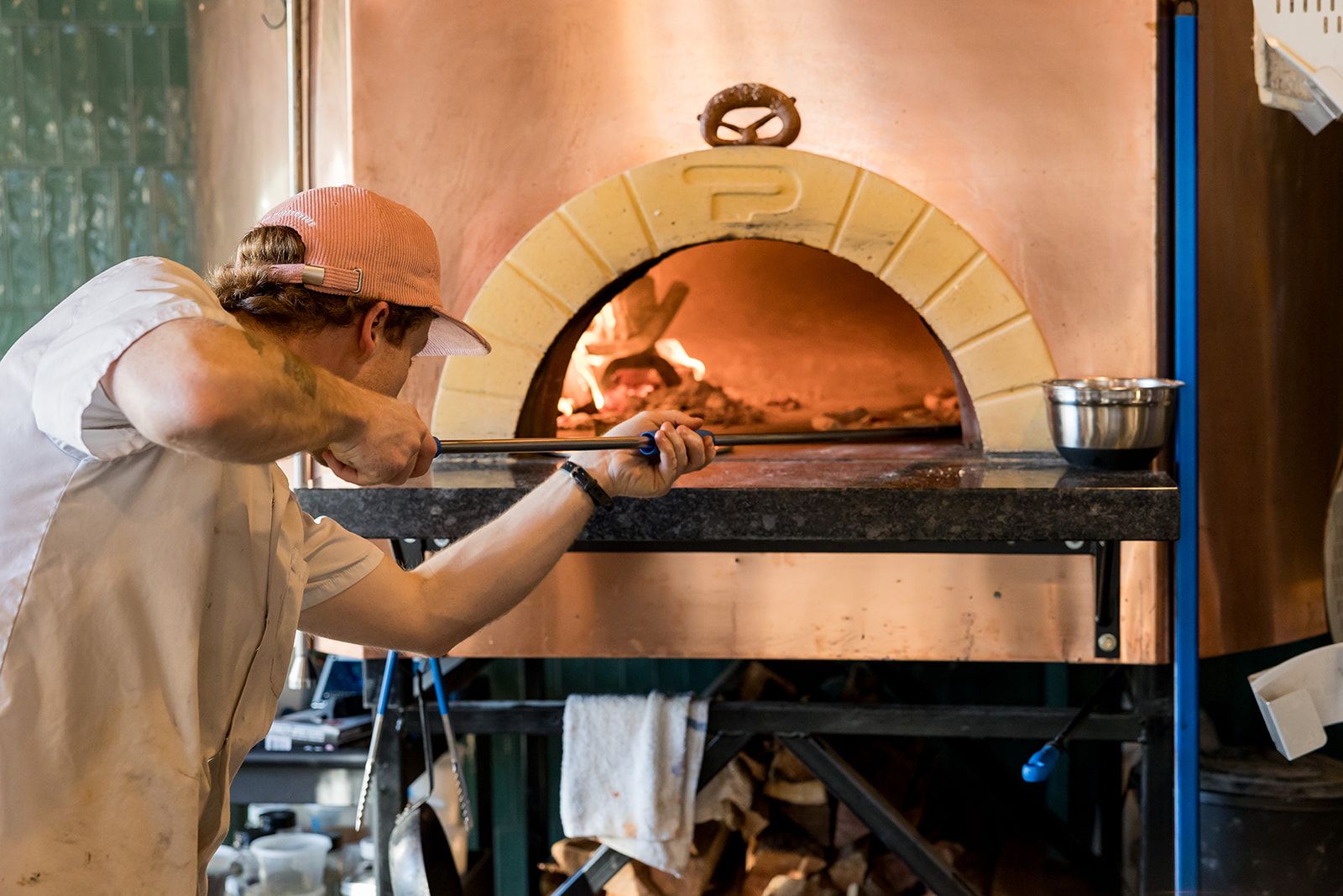 A person puts a pizza into a wood-fire oven.