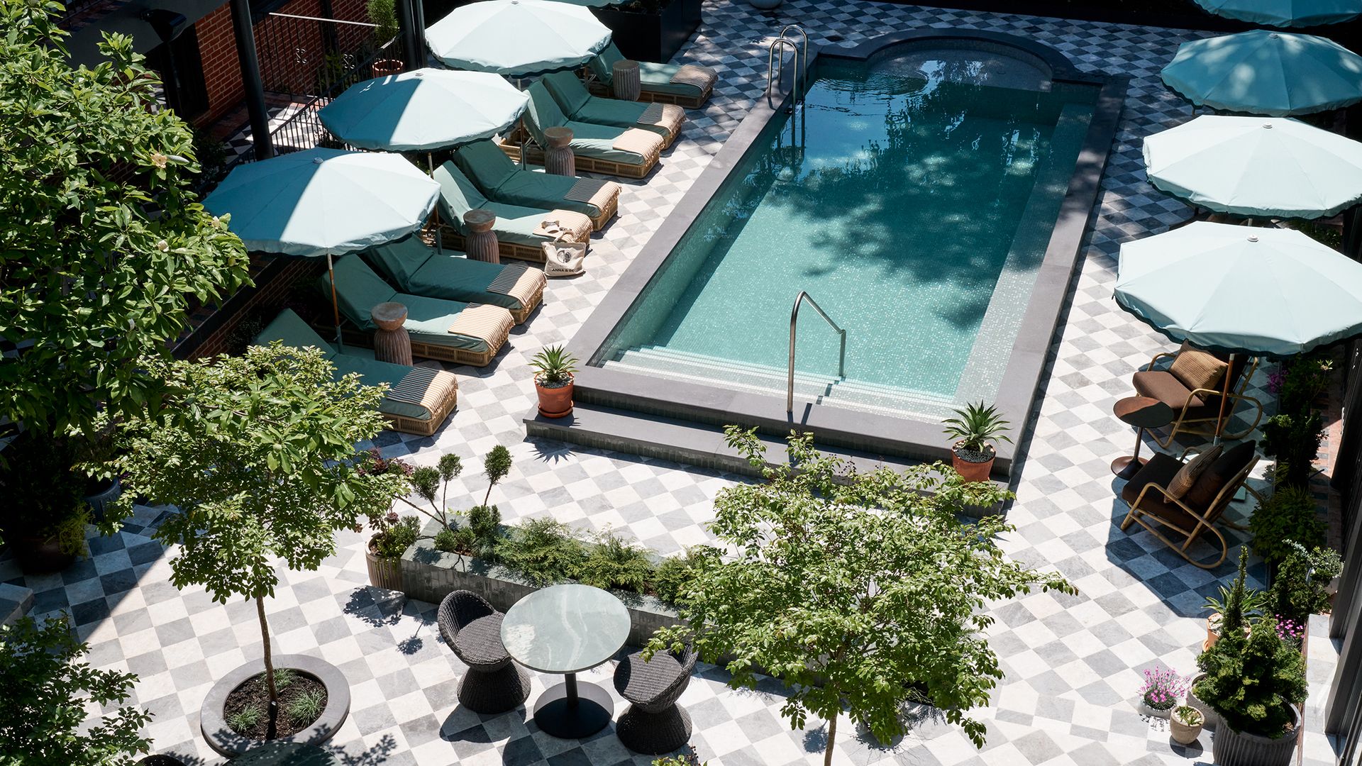 An outdoor pool in a courtyard with gray-and-white checkered tiles.