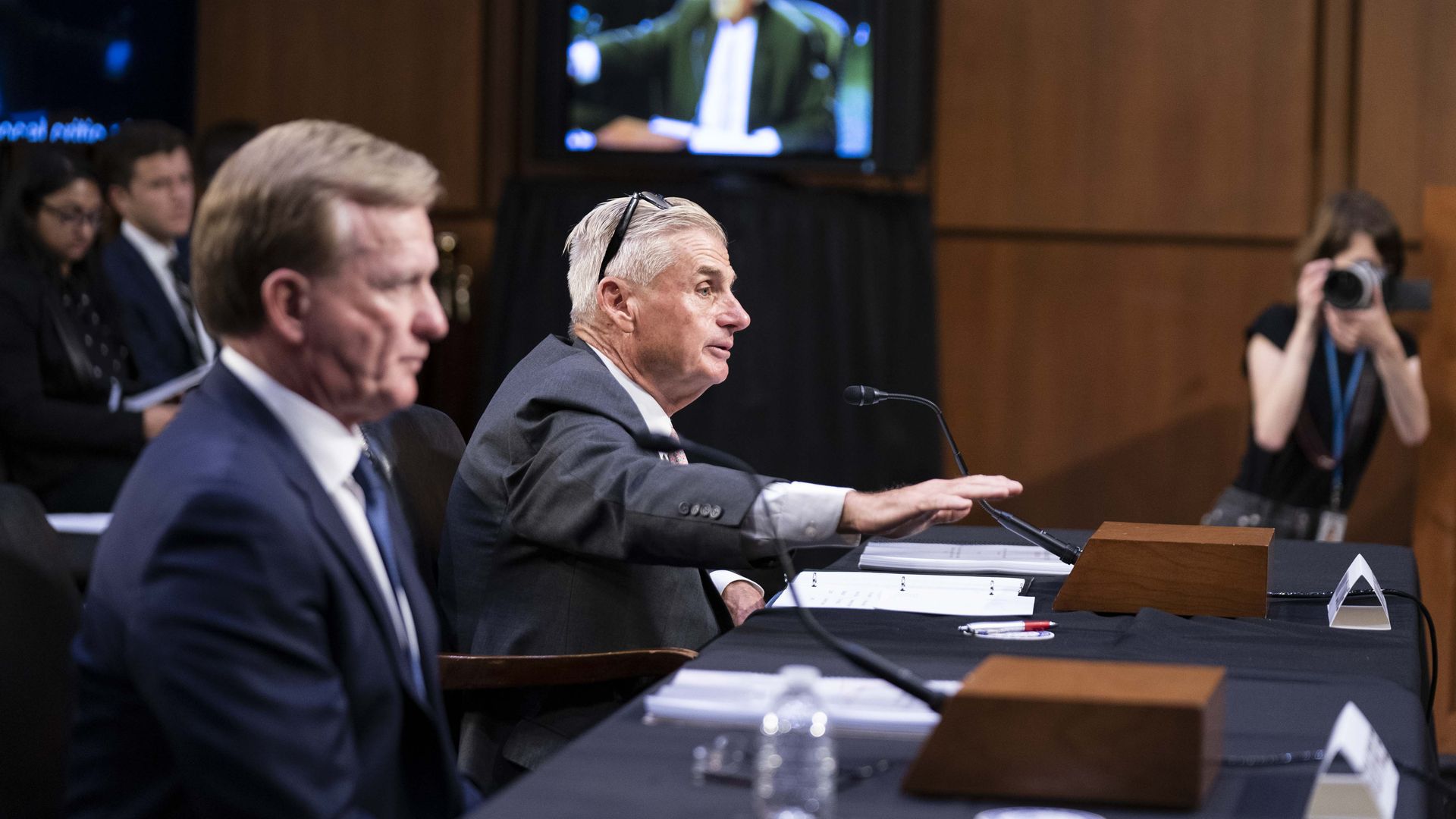 Two men sit at a table at a Senate hearing.