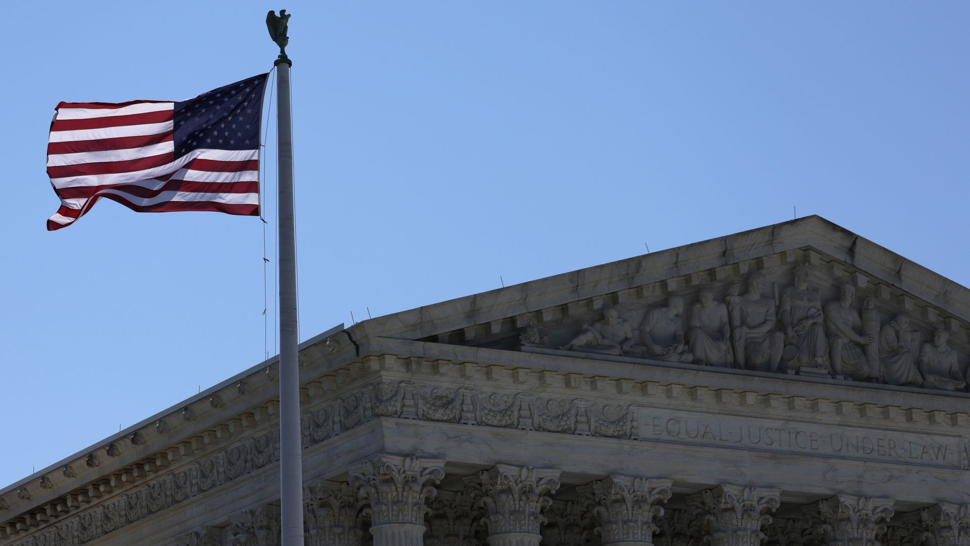 A photograph of the Supreme Court building and an American flag flying in front of it.