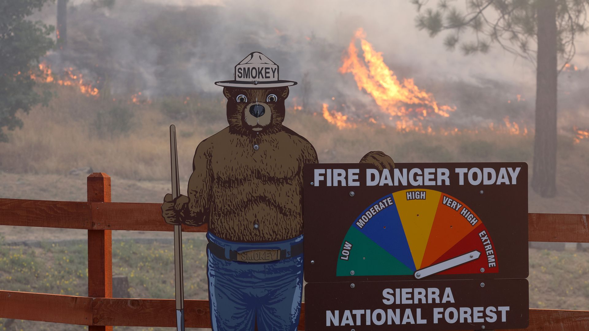Fire burns near a Smokey the Bear fire warning sign as the Oak Fire burns through the area on July 24, 2022 near Jerseydale, California.