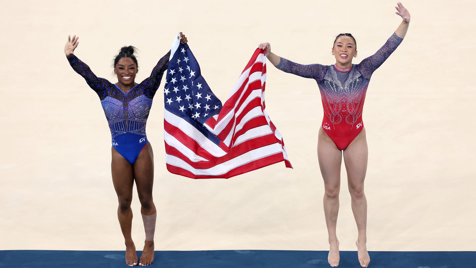 Gold medalist Simone Biles (L) and Bronze medalist Sunisa Lee of Team United States celebrate with the American flag after competing in the Artistic Gymnastics Women's All-Around Final on day six of the Olympic Games Paris 