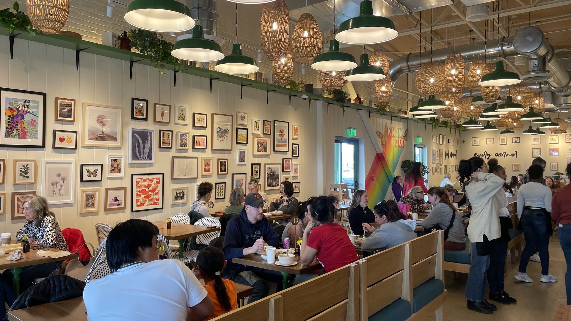 inside Flower Child dining room. People seated at tables, standing by drink dispenser. 