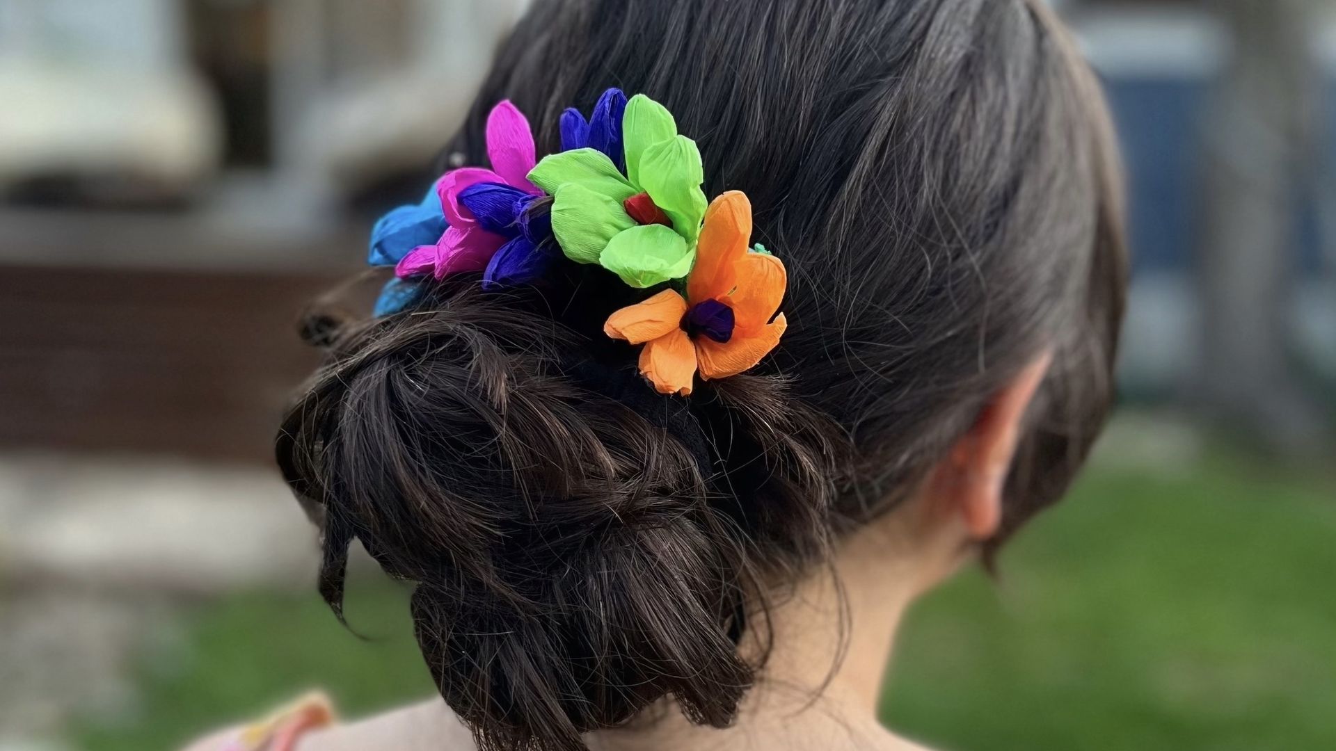 The back of a woman's head with a brightly colored floral hairpiece.