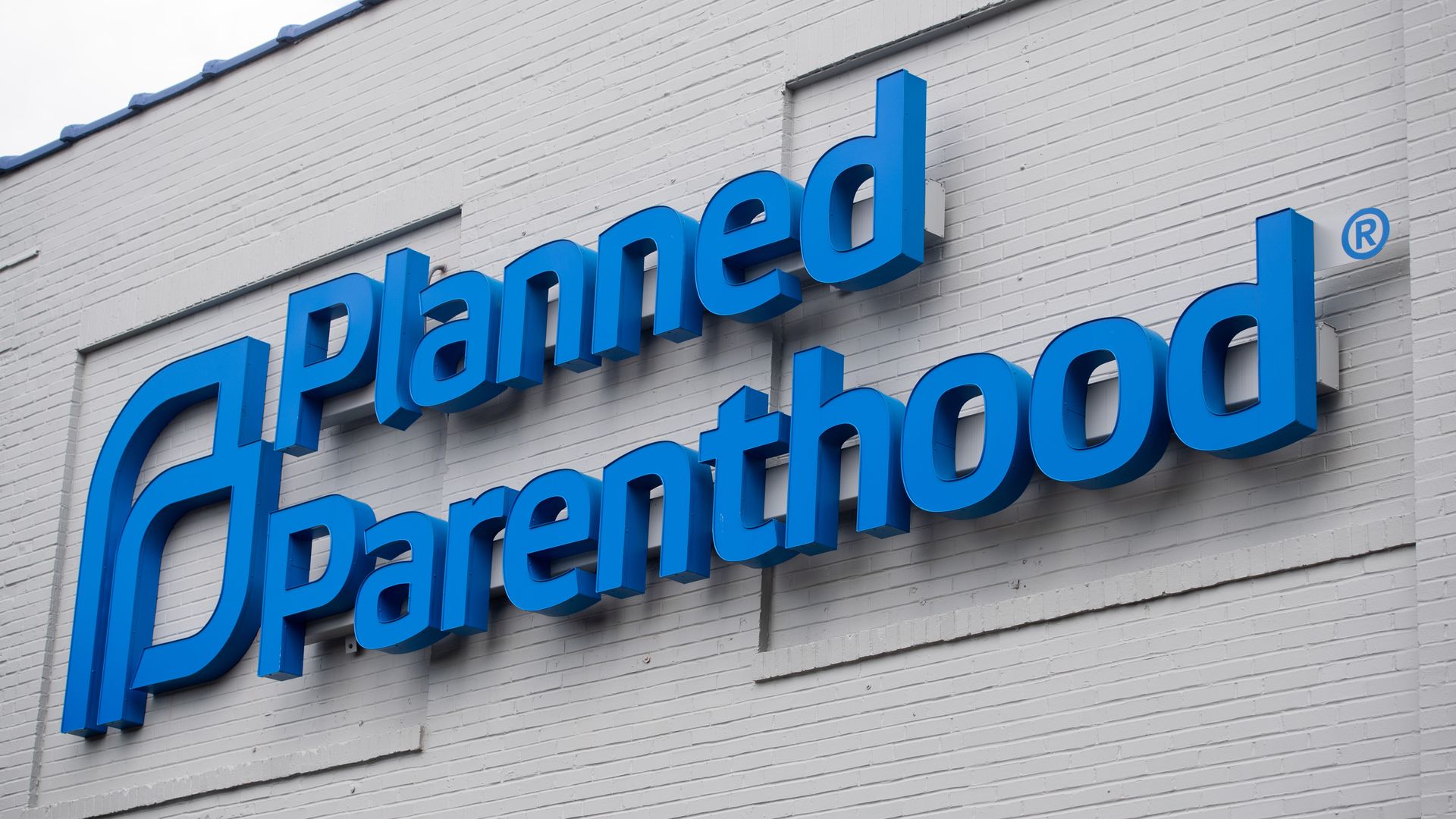 The blue Planned Parenthood logo is seen on a grey, brick building of a Planned Parenthood Reproductive Health Services Center.