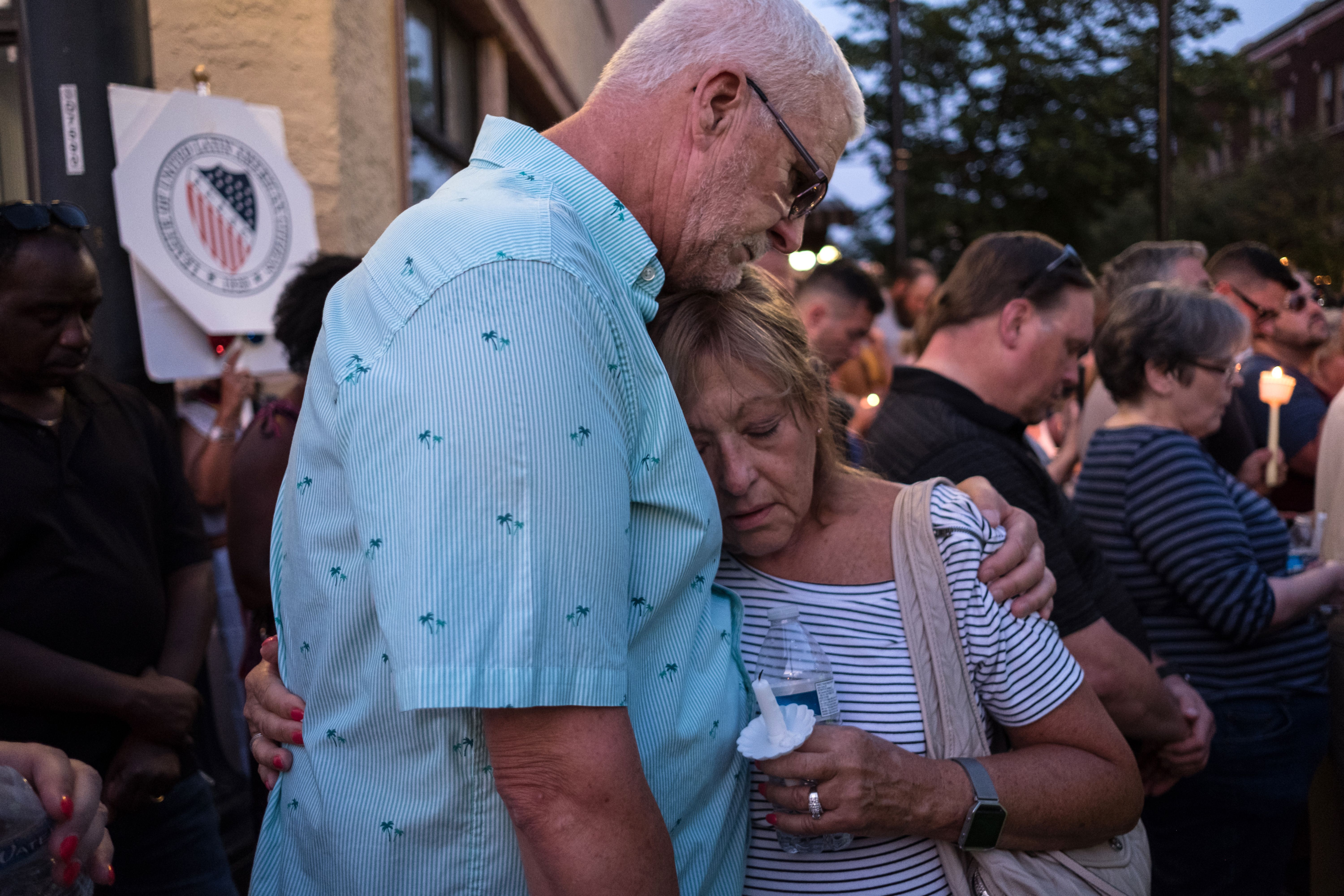 People comfort each other as they take part of a candle lit vigil