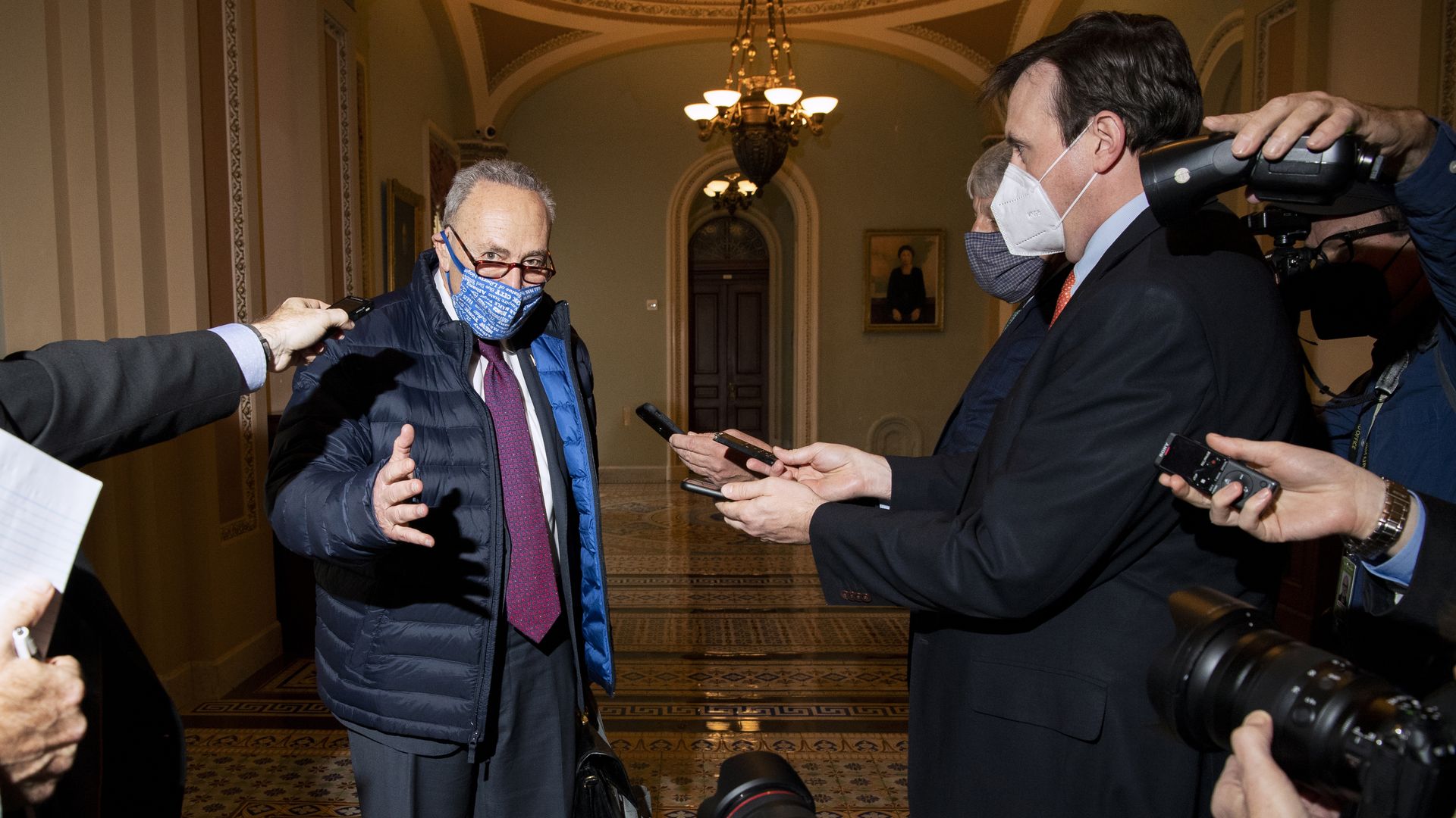 Schumer wears a face mask and speaks to reporters