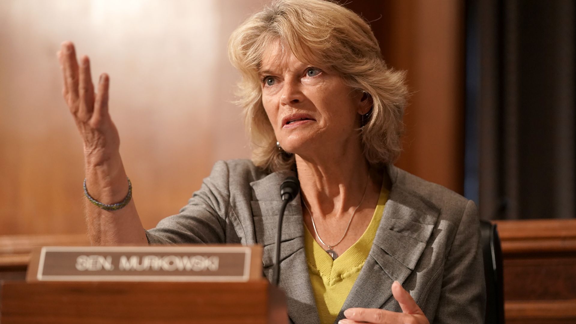 Photo of Lisa Murkowski sitting during a committee hearing with her hand raised while talking