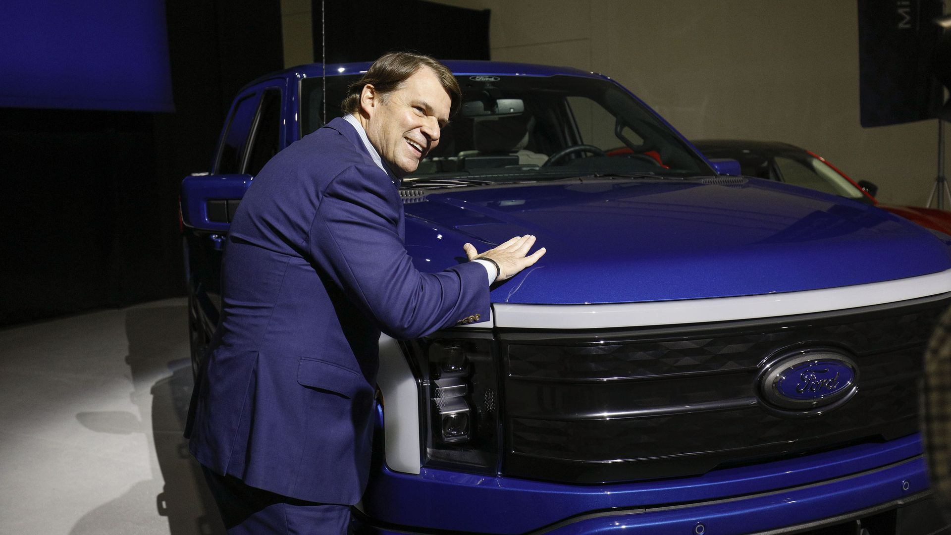 A man pats the hood of a blue pickup truck