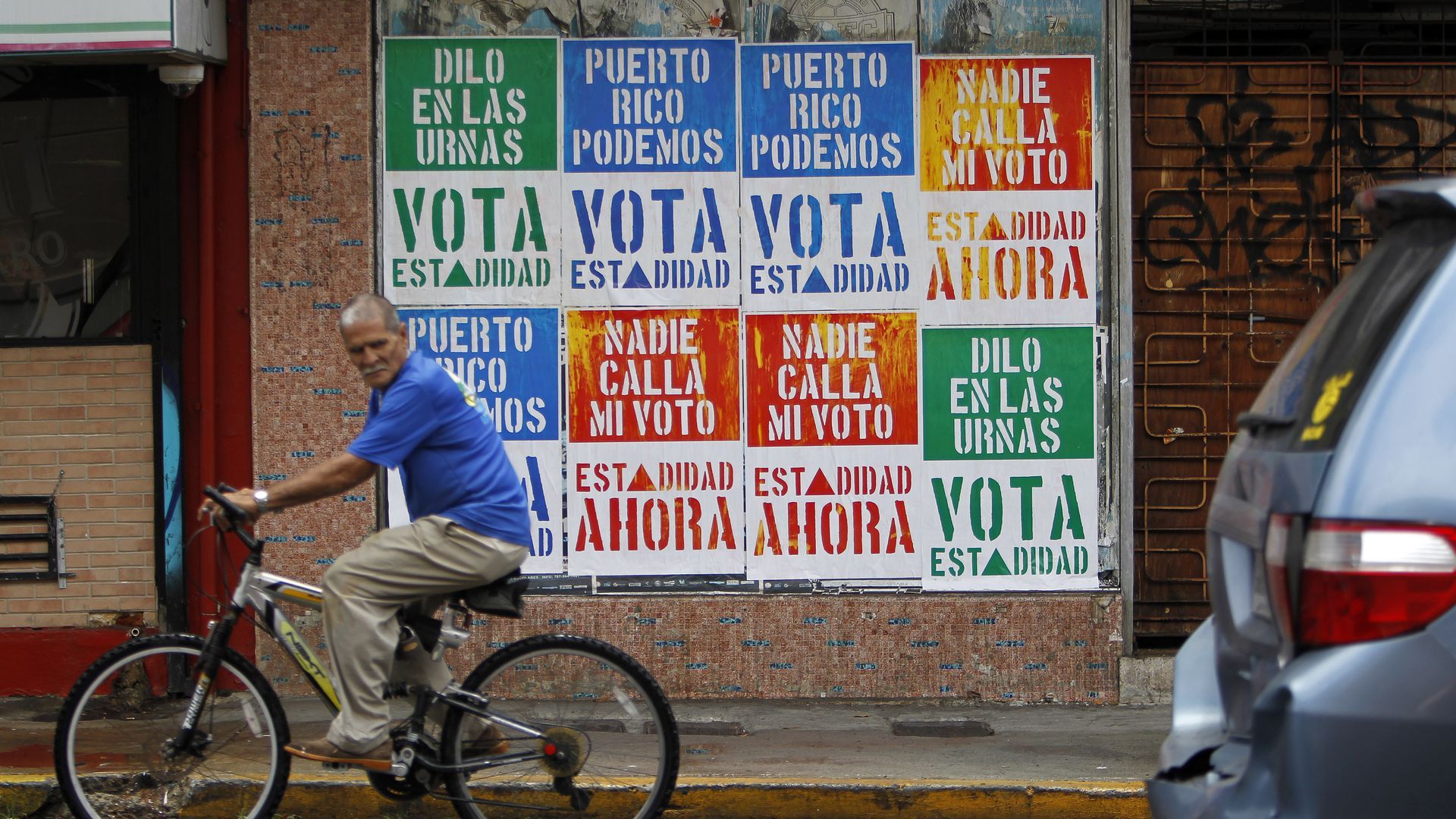 A man rides past signs calling for a vote on Puerto Rican statehood. Photo: Ricardo Arduengo/AFP via Getty Images.