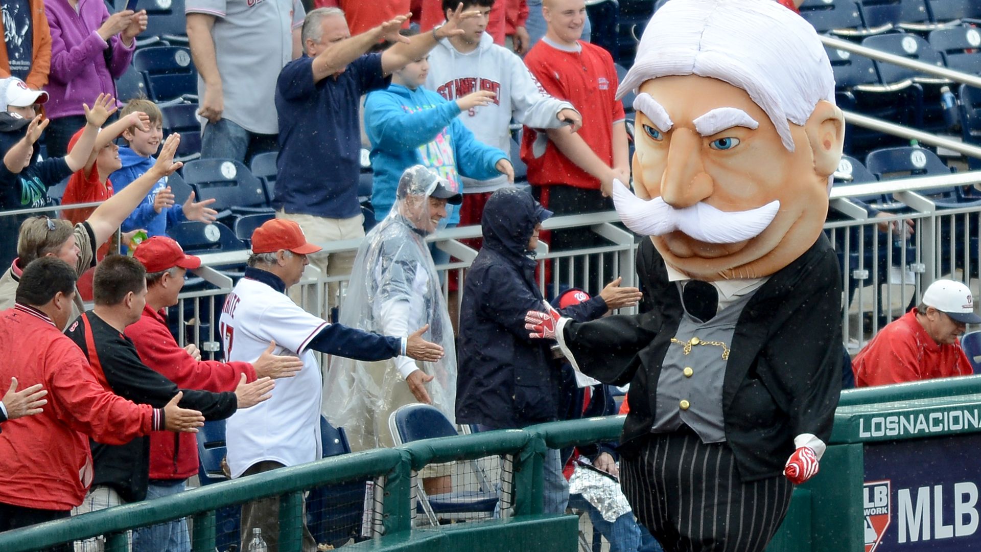 A mascot of William Howard Taft high-fiving baseball fans.