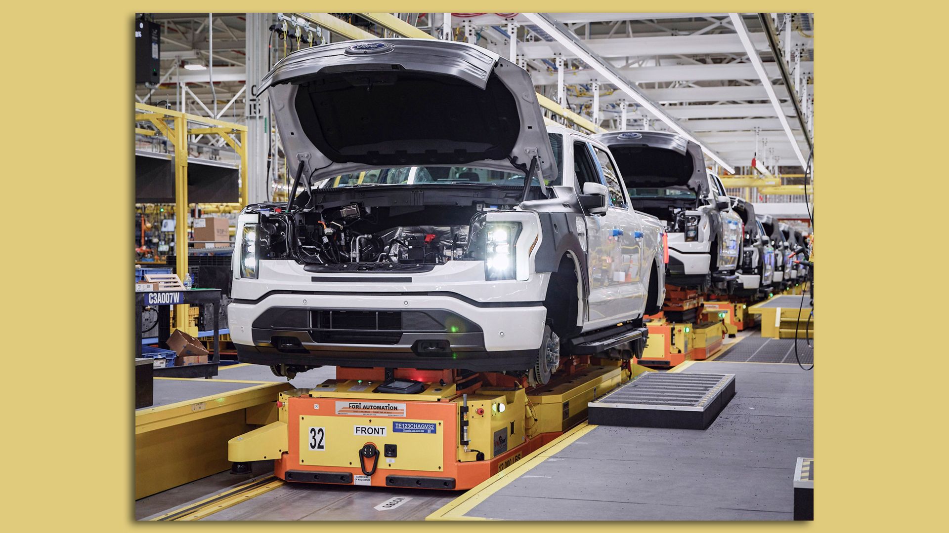 Image of F-150 Lightning trucks being moved by autonomous robots instead of conveyor belts 