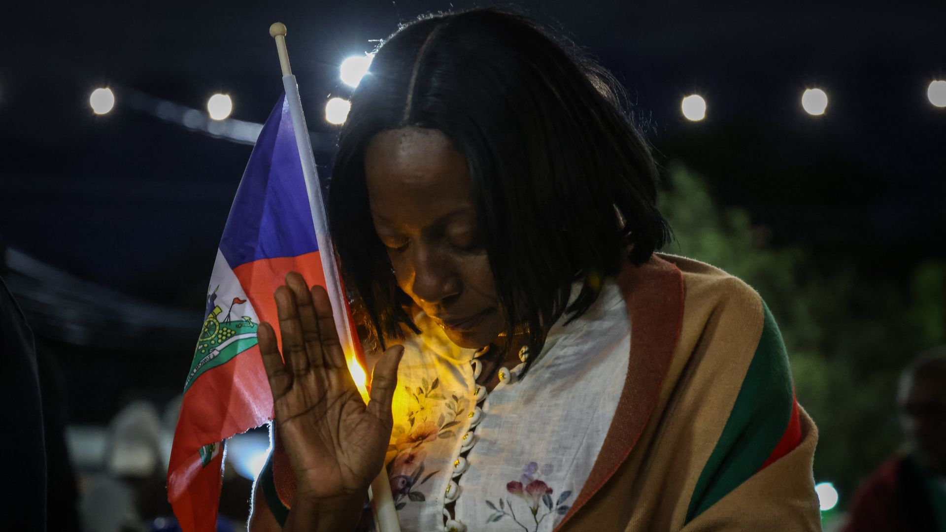 A woman prays during a candlelight vigil for Haitians living in the US under the Temporary Protected Status (TPS) immigration program in Miami, Florida on February 3, 2026. Late on February 2, federal judge Ana C. Reyes of the Federal District Court in Washington, blocked the Trump administration fr