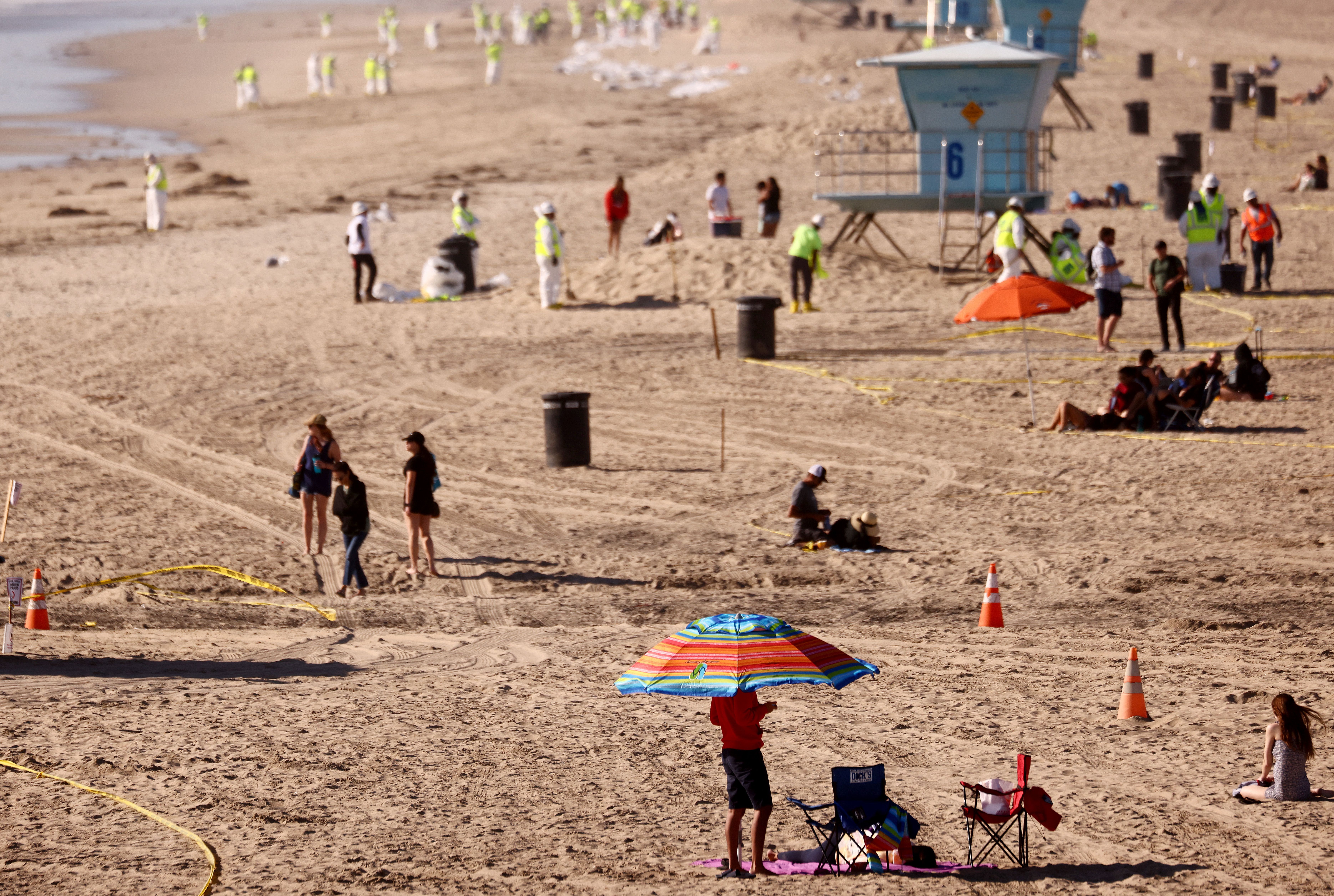  Cleanup crews work around beachgoers on Huntington Beach  on Oct. 9