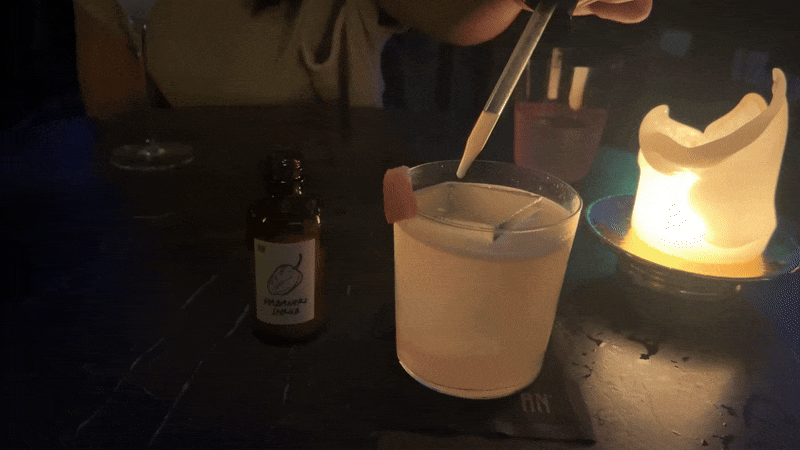 A person adds a dropper of haberno shrub liquid into a cocktail.
