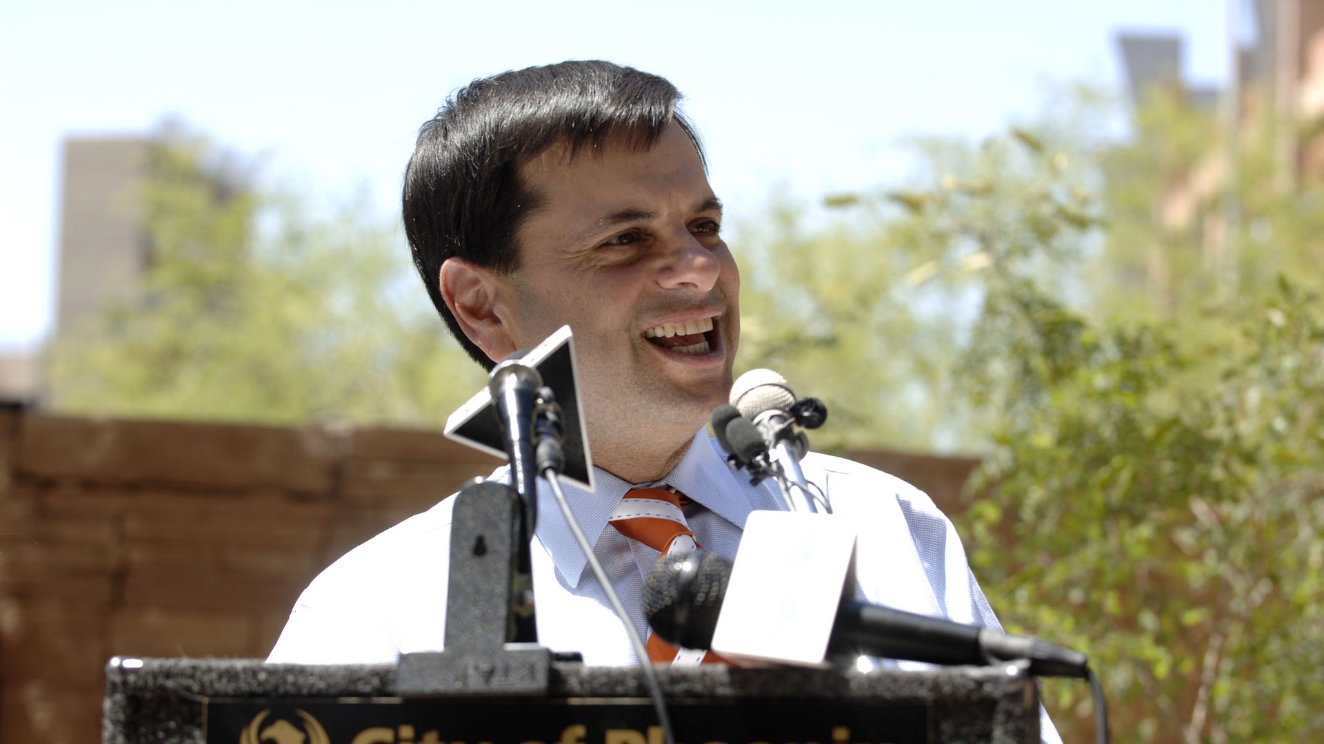 Former Phoenix mayor Phil Gordon smiles at a podium during a press conference