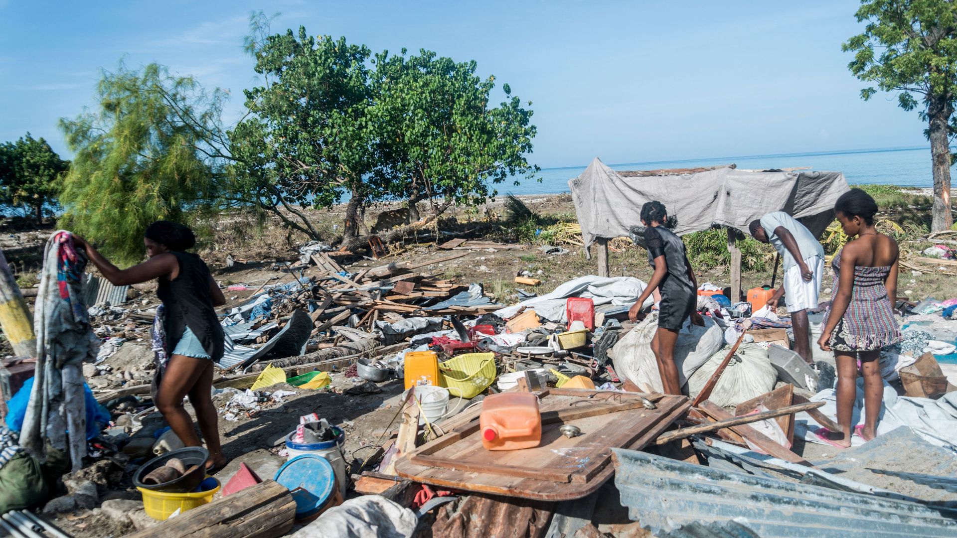 People clean up the remains of their home near the Haitian coast, which was devastated by an earthquake