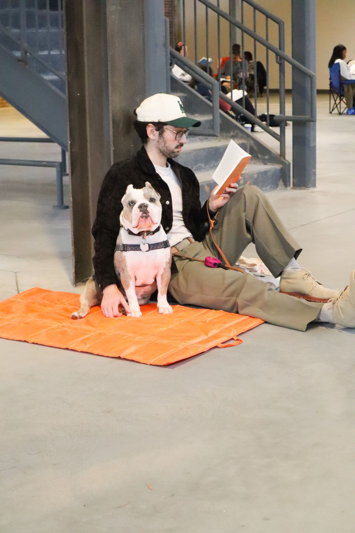 Someone sits on an orange blanket with an arm around their dog while they read at That's Novel Books' silent book club.