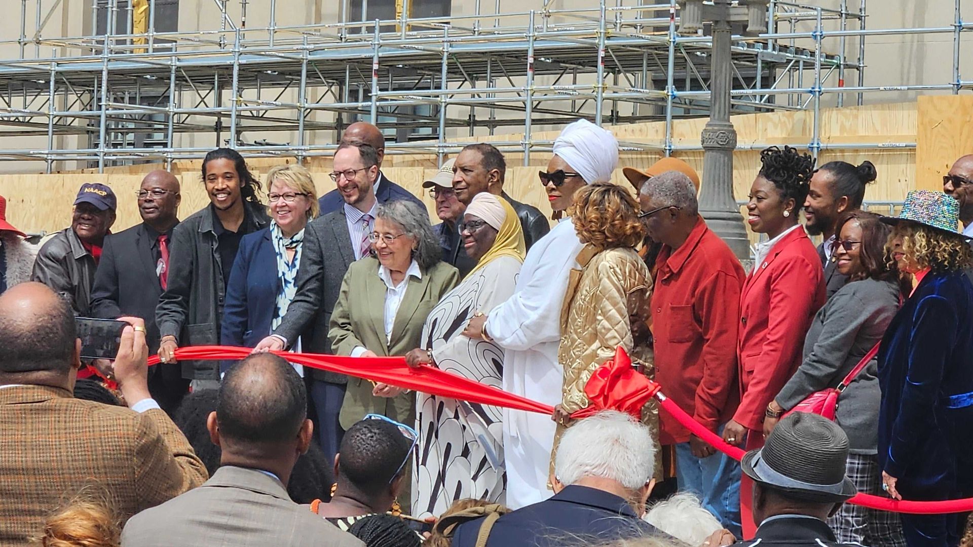 Diane Nash cutting a red ribbon surrounded by people.