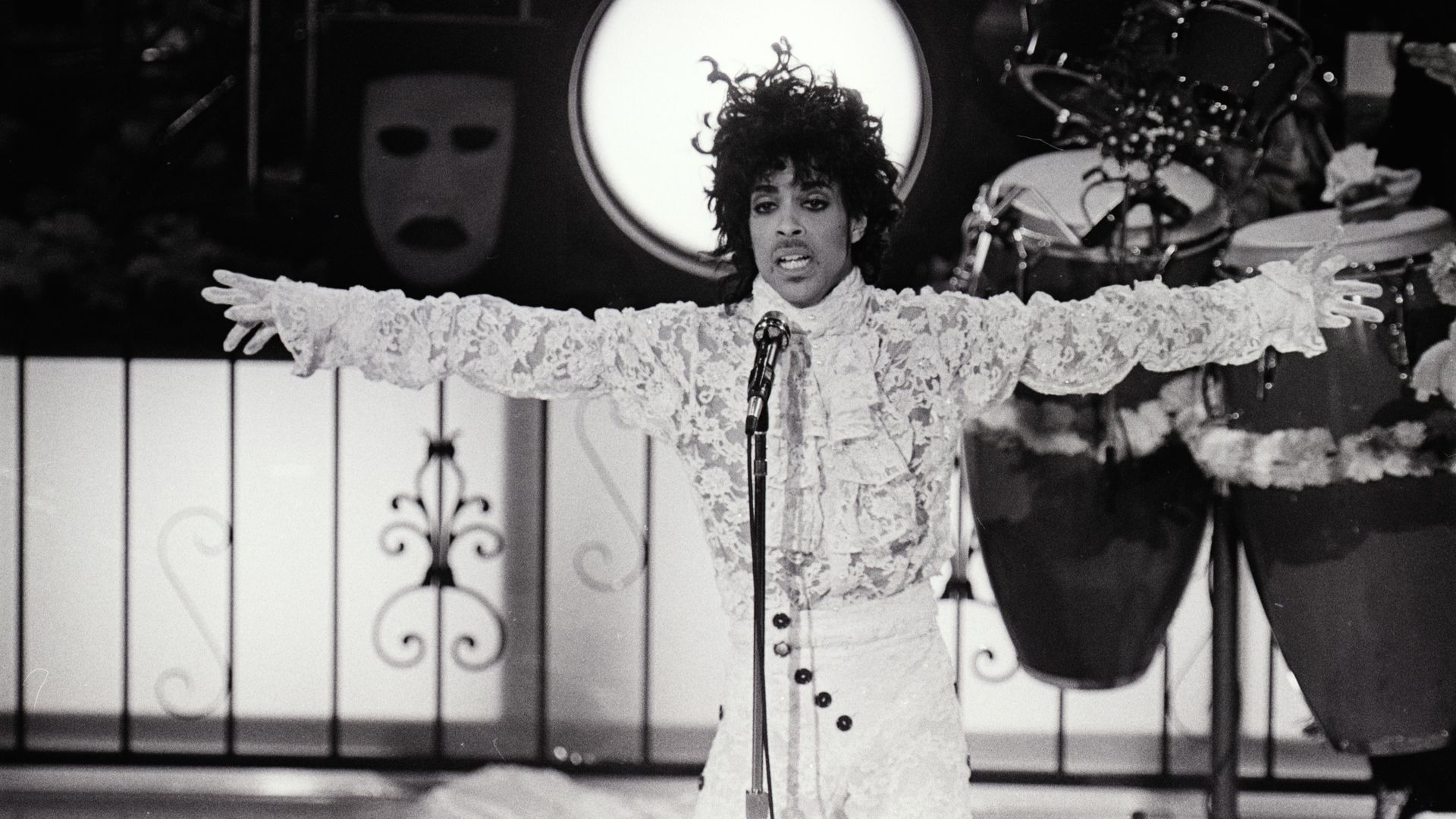 Prince performs on a stage wearing a fluffy white shirt 